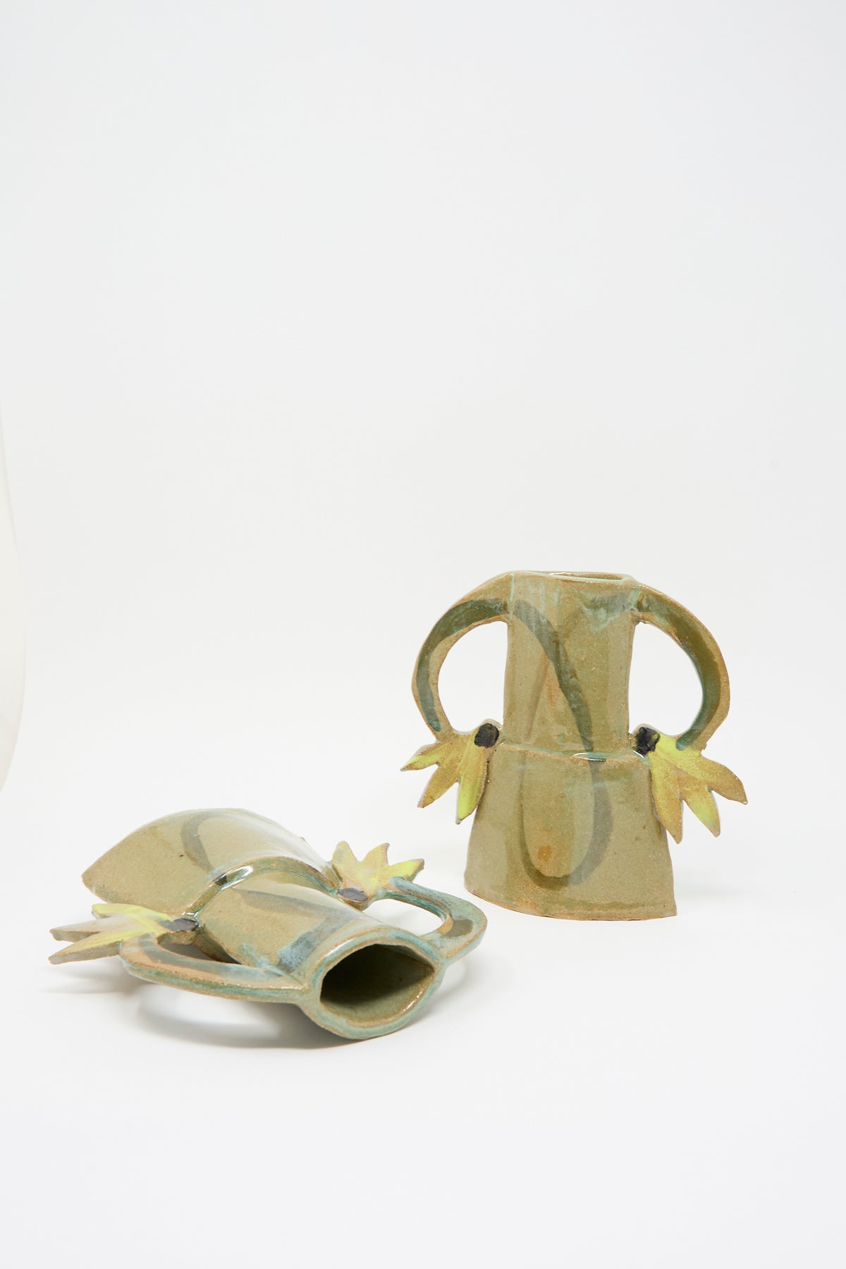 Two Cyclamens Vase in Celadon Green II: handmade celadon green ceramic vases with stylized wing-like handles and small, dark decorative accents.