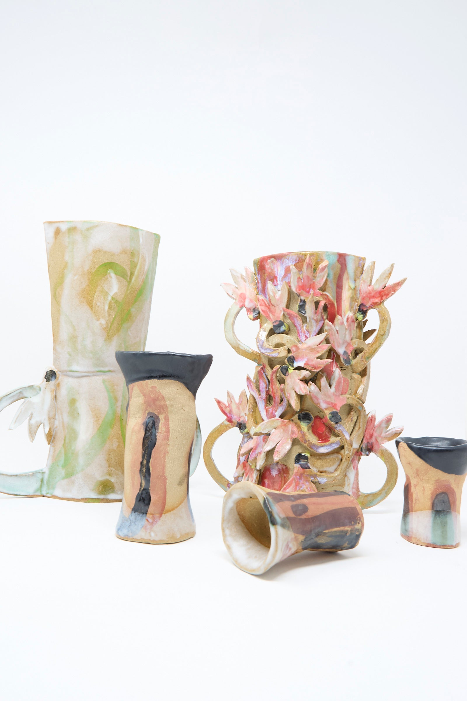 The Two Cyclamens by the Lake Vase from Tamar Mogendorff, featuring hand-painted abstract and floral designs, is styled with matching ceramic mugs on a crisp white surface for a classic Brooklyn aesthetic.