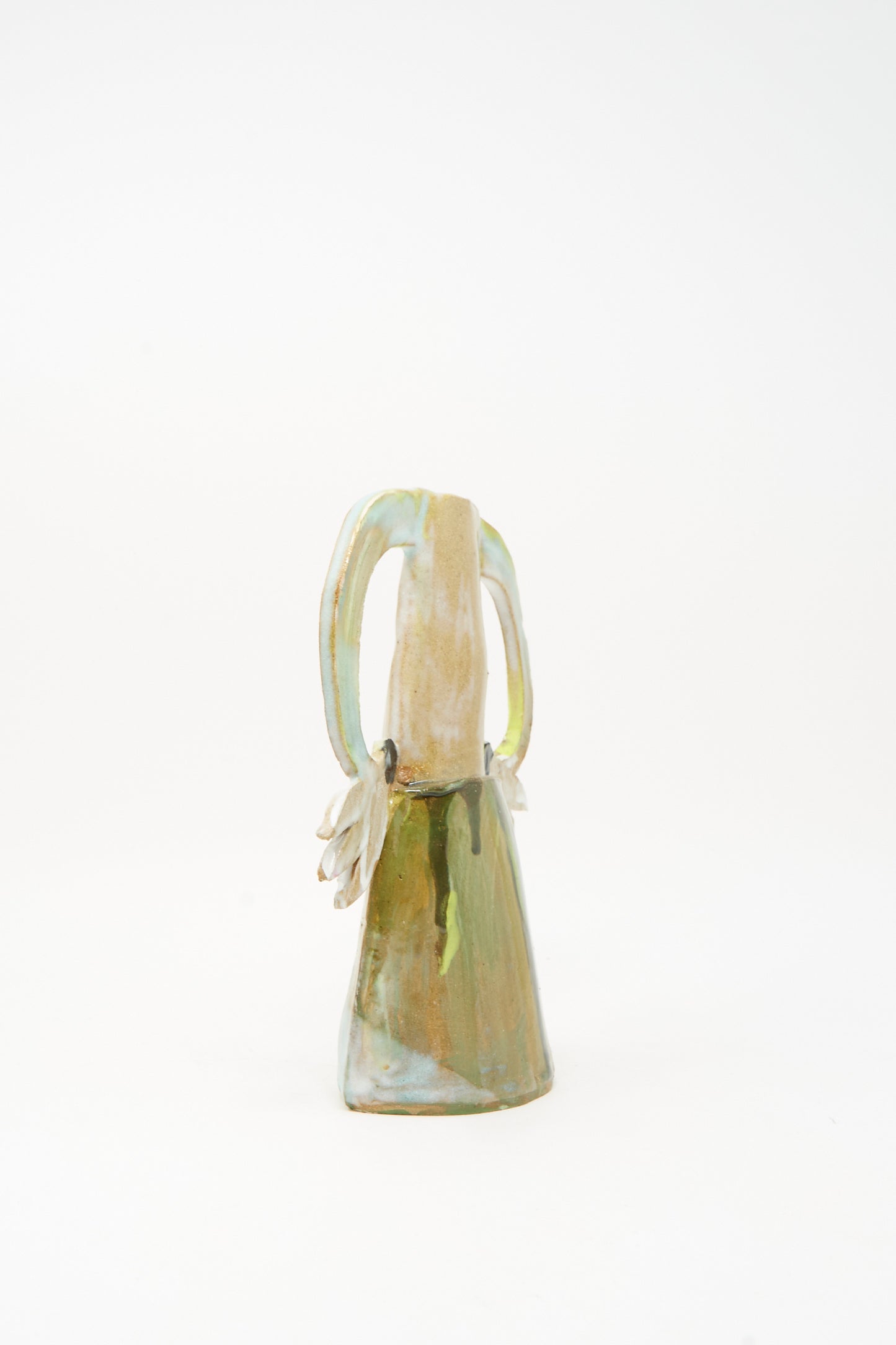The "Two Cyclamens on Top of a Mountain Vase III" by Tamar Mogendorff is a handmade ceramic vase with an elongated neck, two looped handles, and an irregular base. Featuring earth-toned glazes with hints of green-blue, it stands against a plain white background.
