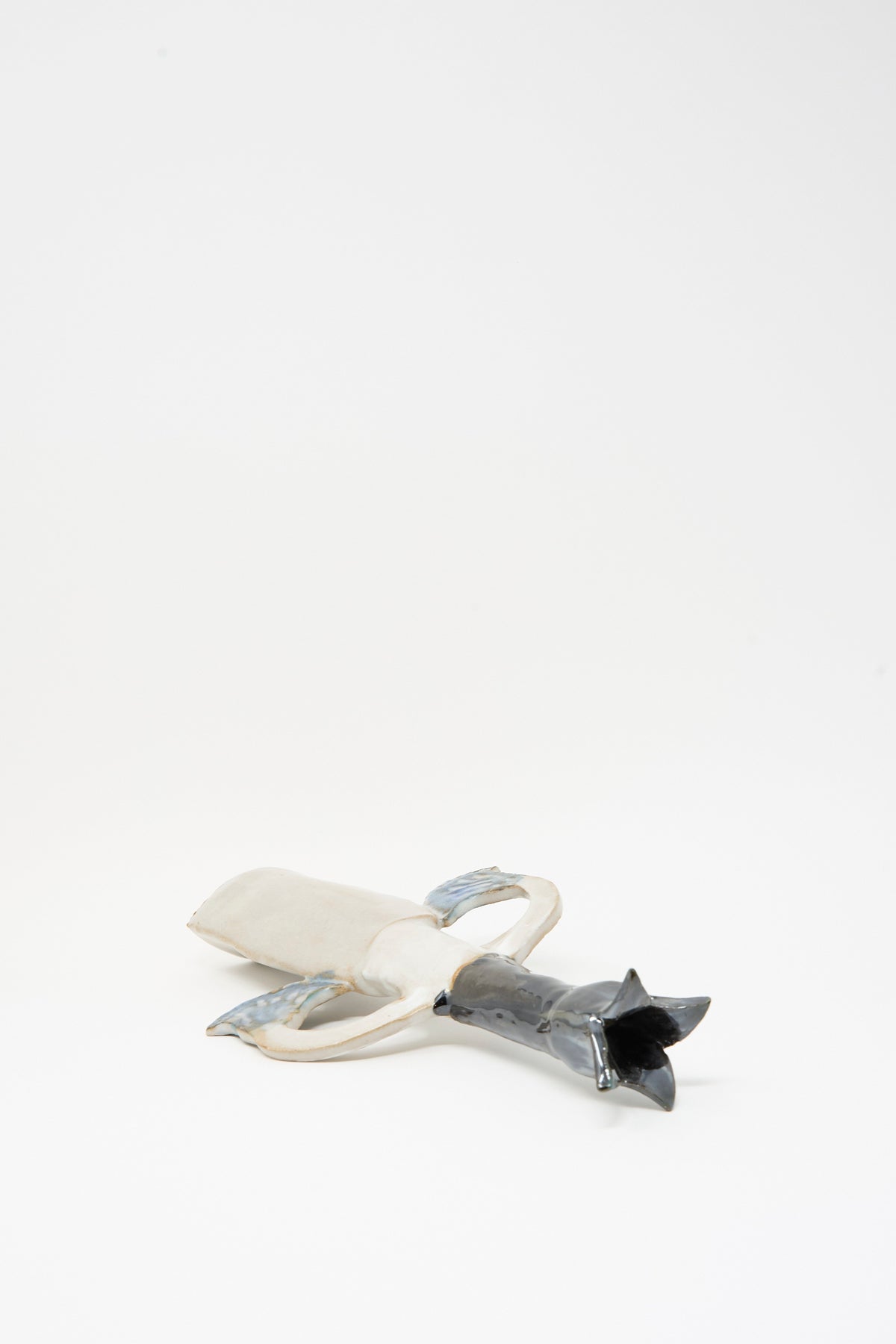 Tamar Mogendorff Two Papyrus Candle Holder, a handmade ceramic piece shaped like a figure with a light-colored base and a dark, pointed top featuring a multicolored glaze.