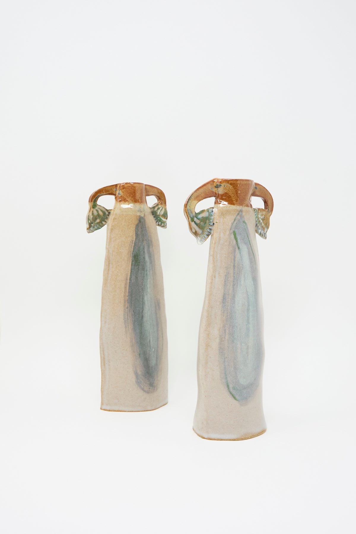 Two Papyrus Candle Holders, a pair of tall, slender handmade ceramic pieces with flared handles and muted blue and tan multicolored glaze details.