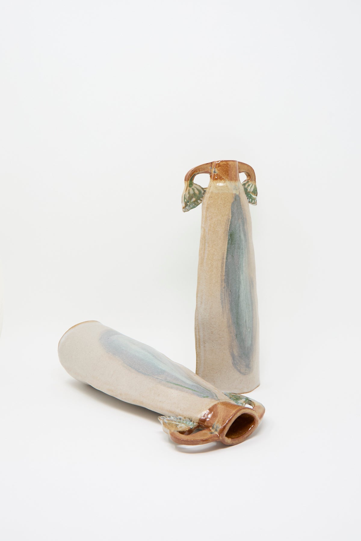 Two Papyrus Candle Holders set featuring tall, slender handmade ceramic holders with multicolored glaze and side handles, one standing upright and one lying on its side.