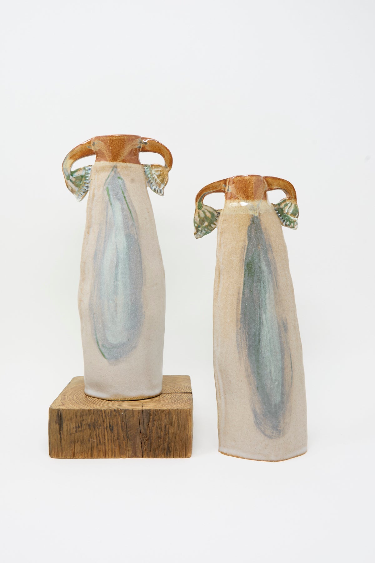 Two Papyrus Candle Holders Set consisting of tall, slender, multicolored glazed ceramic vessels with flared handles and blue-green brushwork, one resting on a square wooden block.