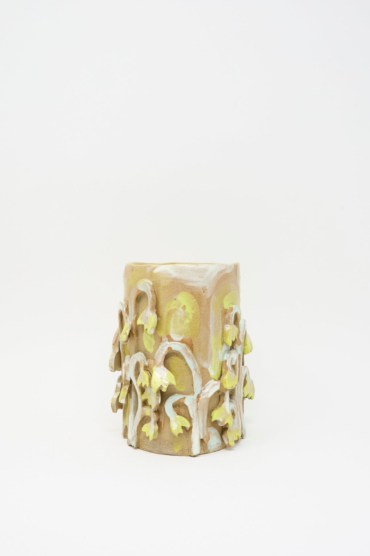 Yellow Fritillaria Vase by Tamar Mogendorff, a cylindrical handmade ceramic vase decorated with raised, pale yellow flower carvings.