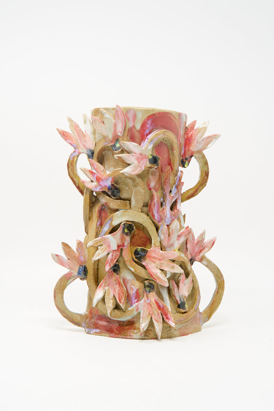 The Cyclamens in the Wild Vase by Tamar Mogendorff features pink and white flower-inspired sculptures and twisting, vine-like handles, making this handmade piece a striking standout against a plain white background.