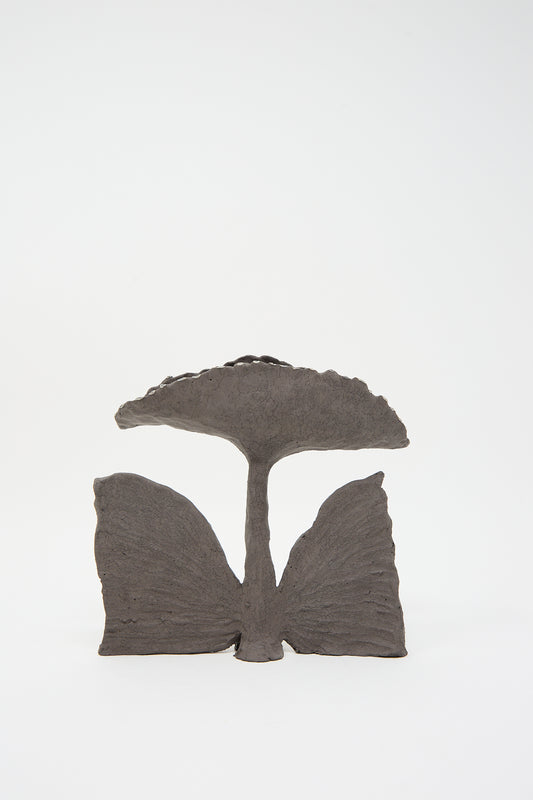 A Tania Whalen Petite Gingko Flower Sculpture, resembling a minimalist, abstract mushroom with a wider cap, handcrafted in Brooklyn from dark stoneware, set against a plain white background.