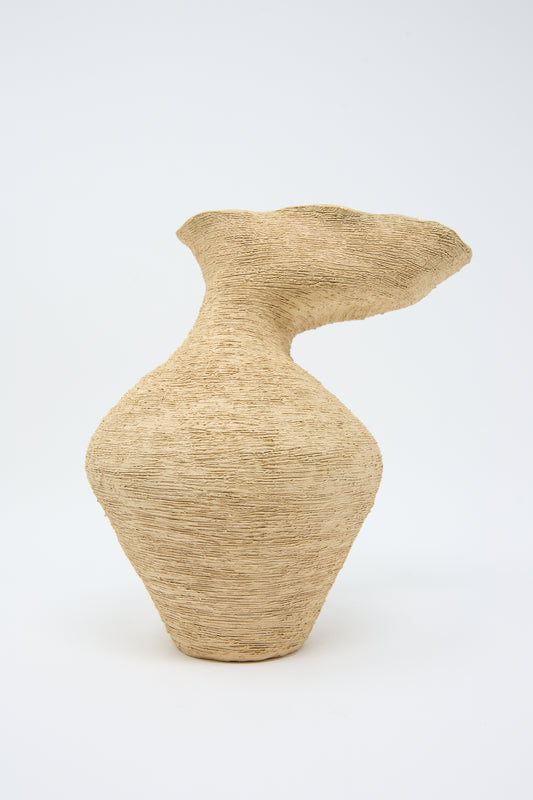 Beige, hand-built vase with a wide base, narrow neck, and asymmetrical, flaring rim, boasting a raw surface finish. (The Flutter Vase in Sand by Tania Whalen)