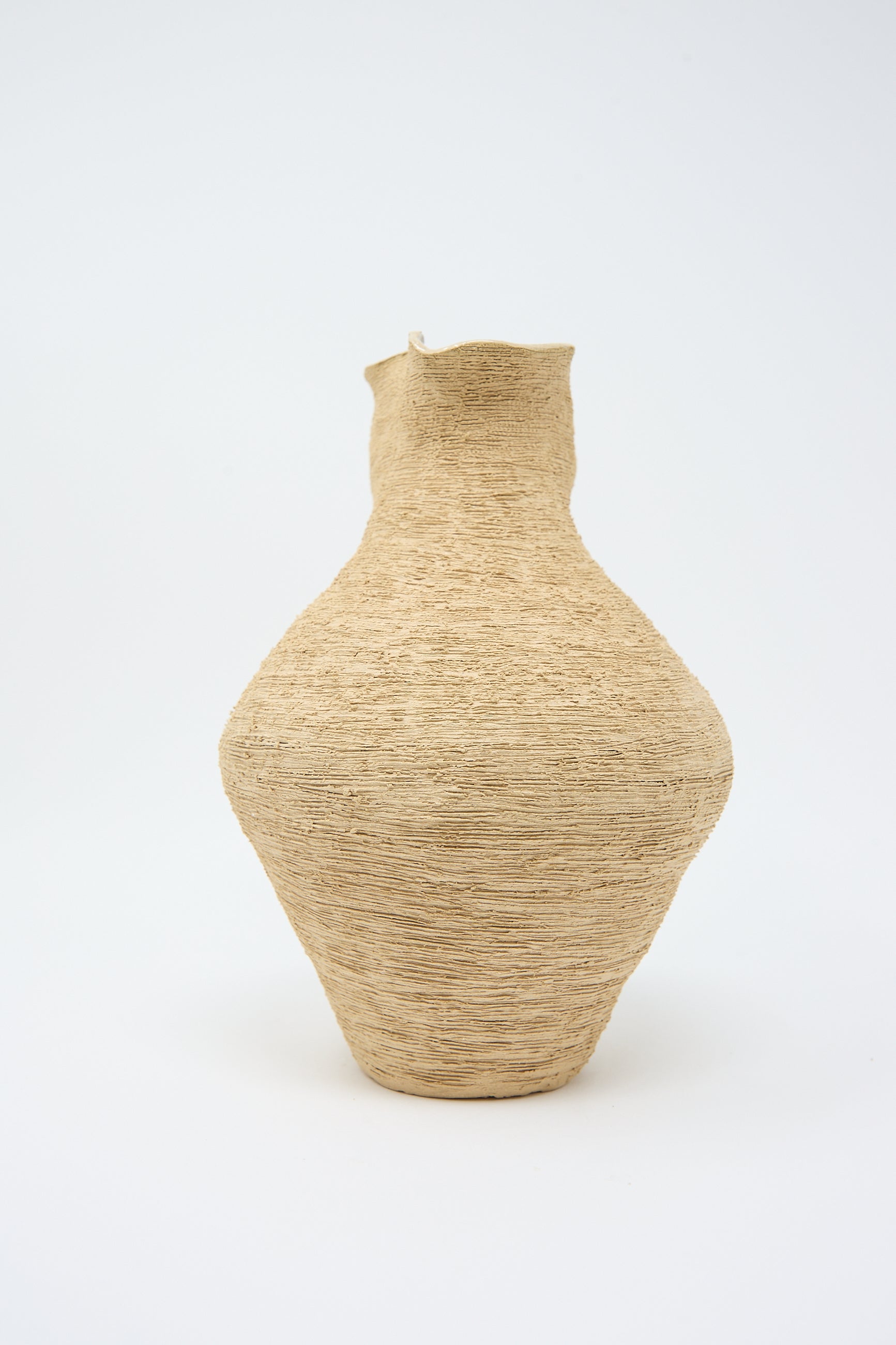 A tall, hand-built vase with a raw surface finish, showcasing a wide body, narrow neck, and slightly flared rim. Crafted from textured sand stoneware, The Flutter Vase in Sand by Tania Whalen stands gracefully against a plain white background.