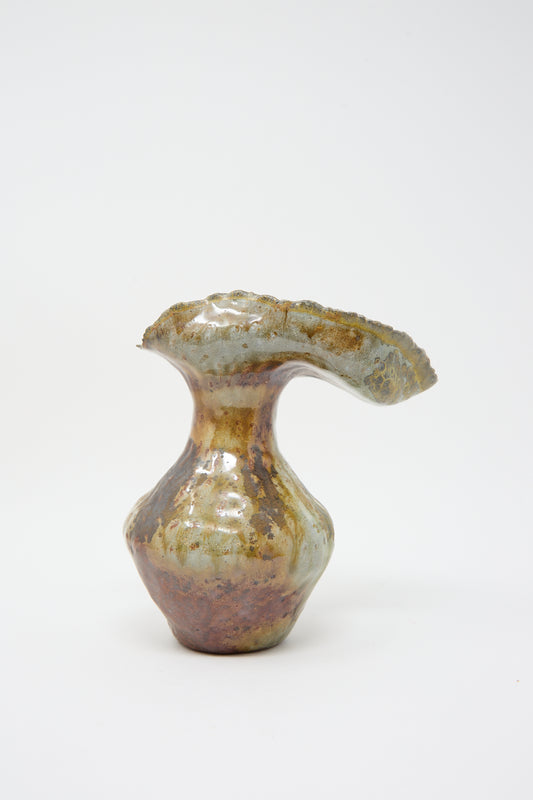 A Tania Whalen The Small Woodfired Flutter Vase with a ruffled opening and an iridescent, multi-colored glaze on a white background.