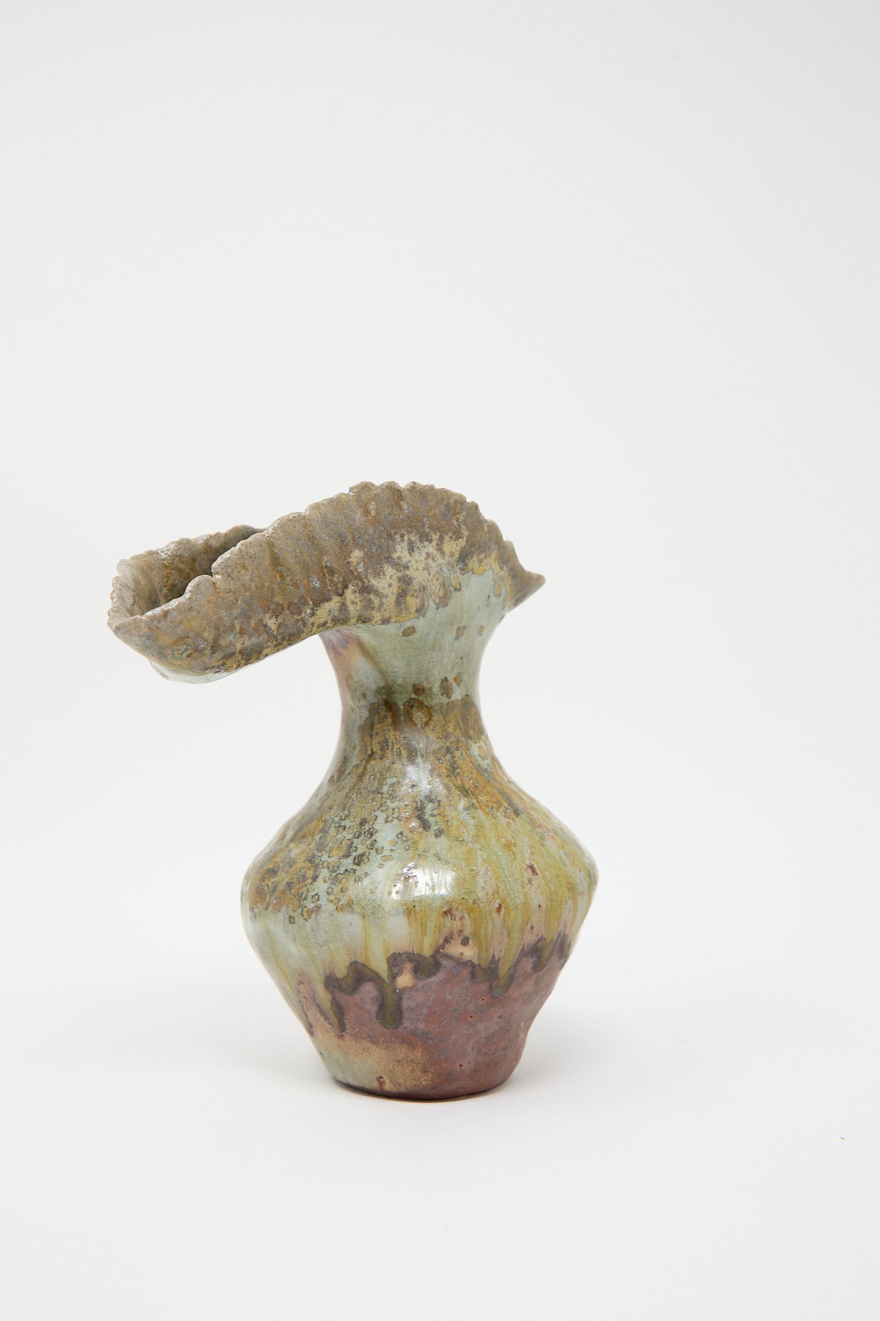 A Tania Whalen Small Woodfired Flutter Vase with a twisted, ruffled opening and an irregular glaze in shades of green, brown, and beige, set against a plain white background.