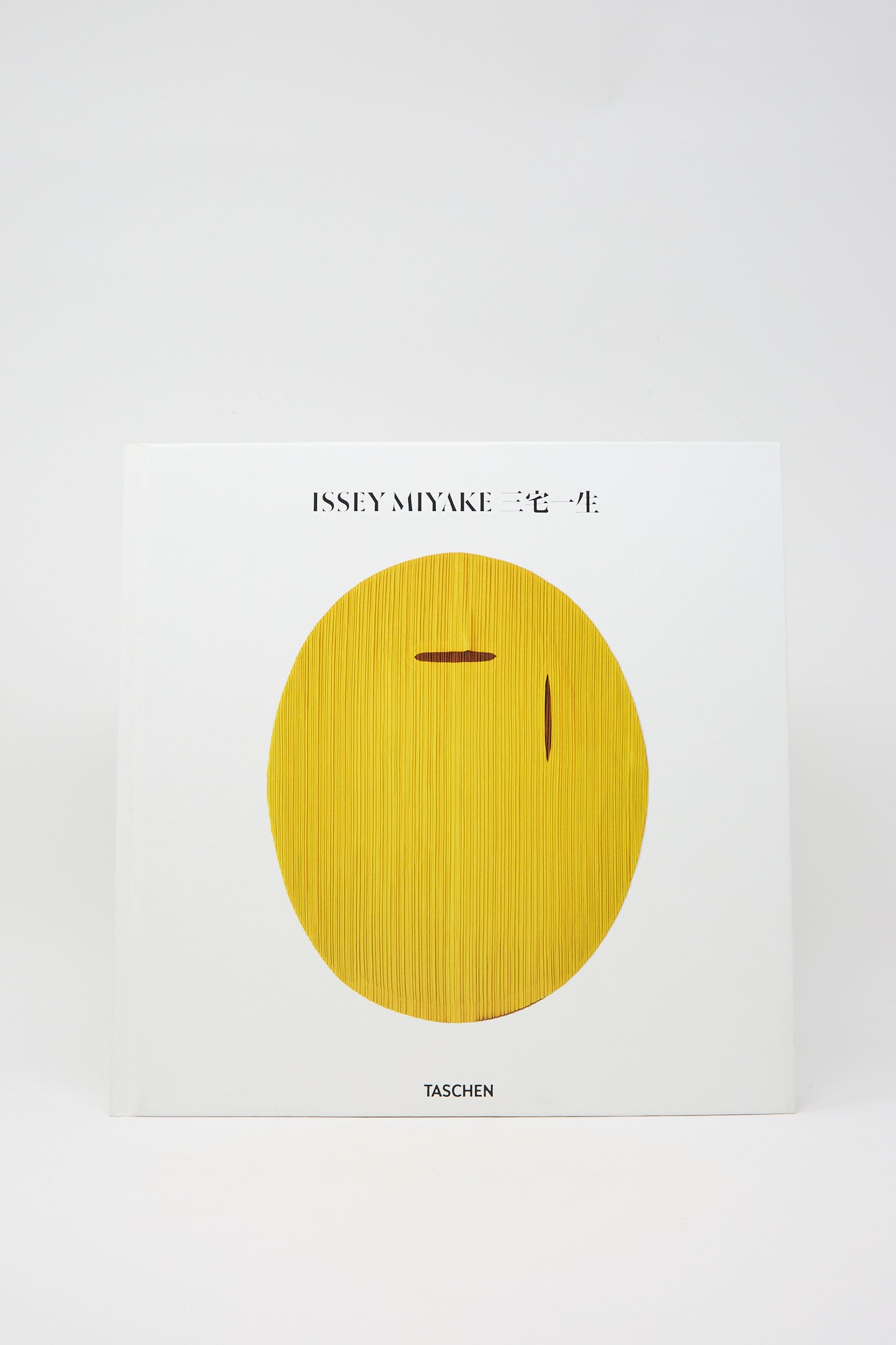 The cover of the book "Issey Miyake" by Taschen showcasing an abstract yellow oval shape on a white background.