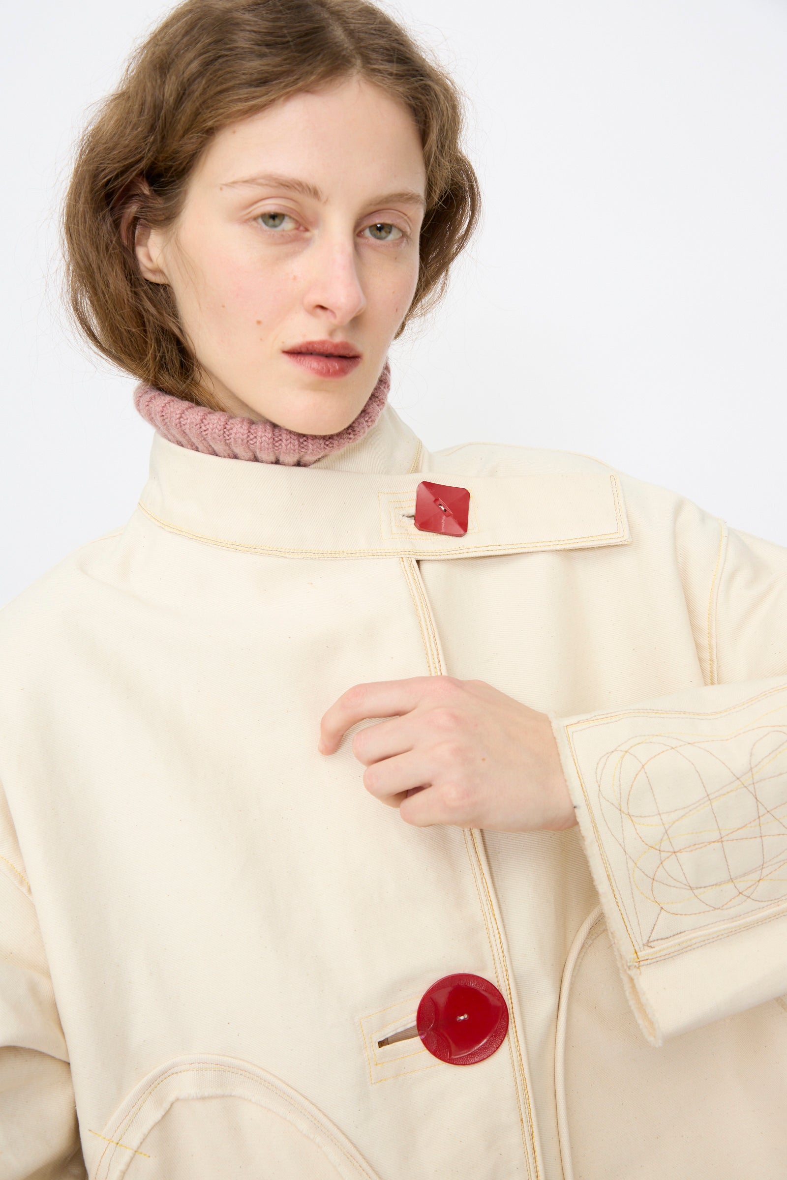 A person modeling the Thank You Have A Good Day Denim Fishtail Parka in Ecru, styled with a pink turtleneck, poses against a plain white background.