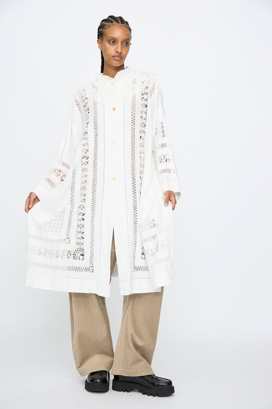 A person stands against a white background wearing the Ruffle Oversized Oxford shirt by Thank You Have A Good Day, paired with beige wide-leg pants and black shoes.