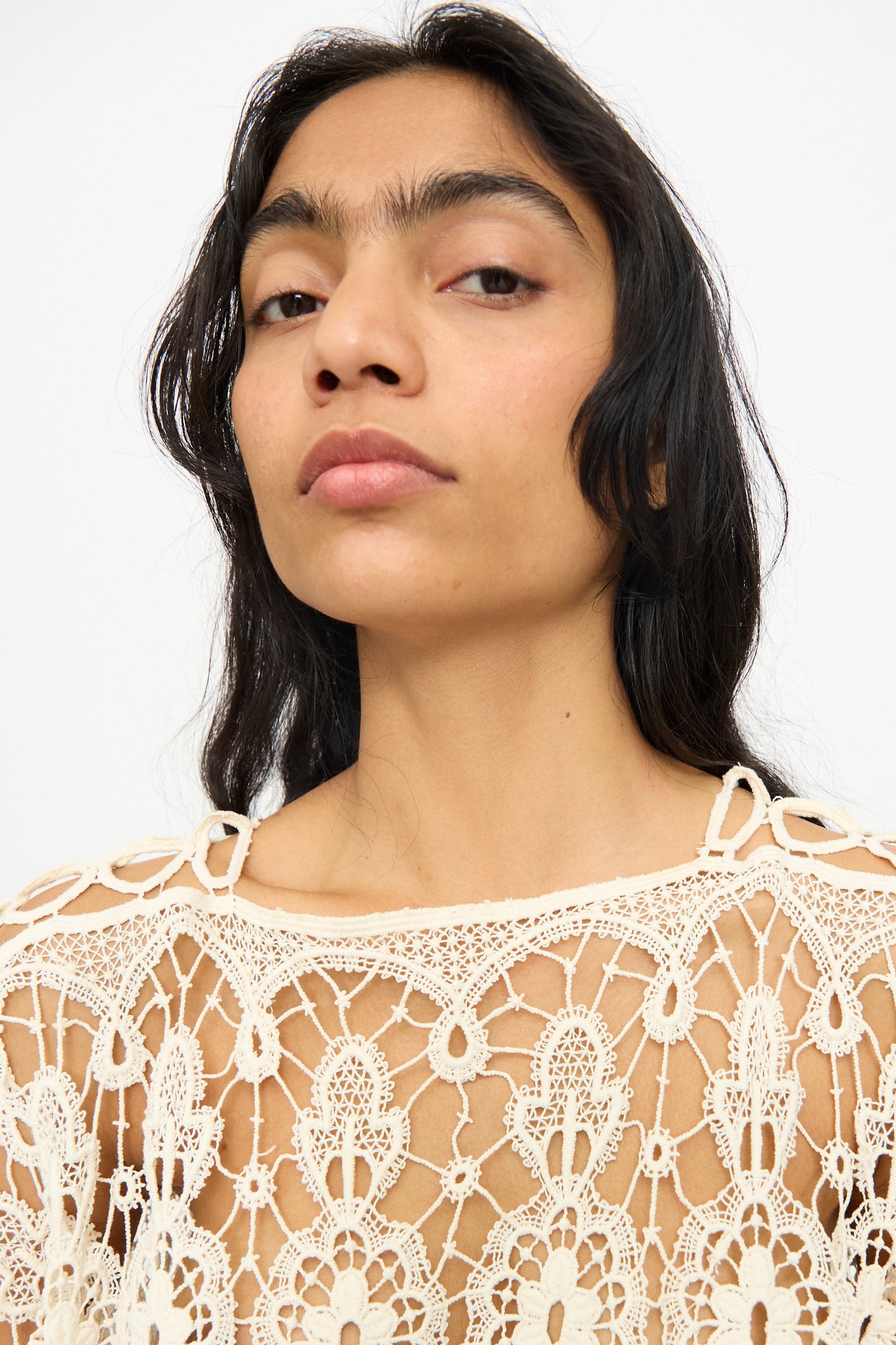 A person with long dark hair models the Antique Lace Midi Caftan by Thank You Have A Good Day, featuring intricate crochet in cream, and looks into the camera against a plain background.