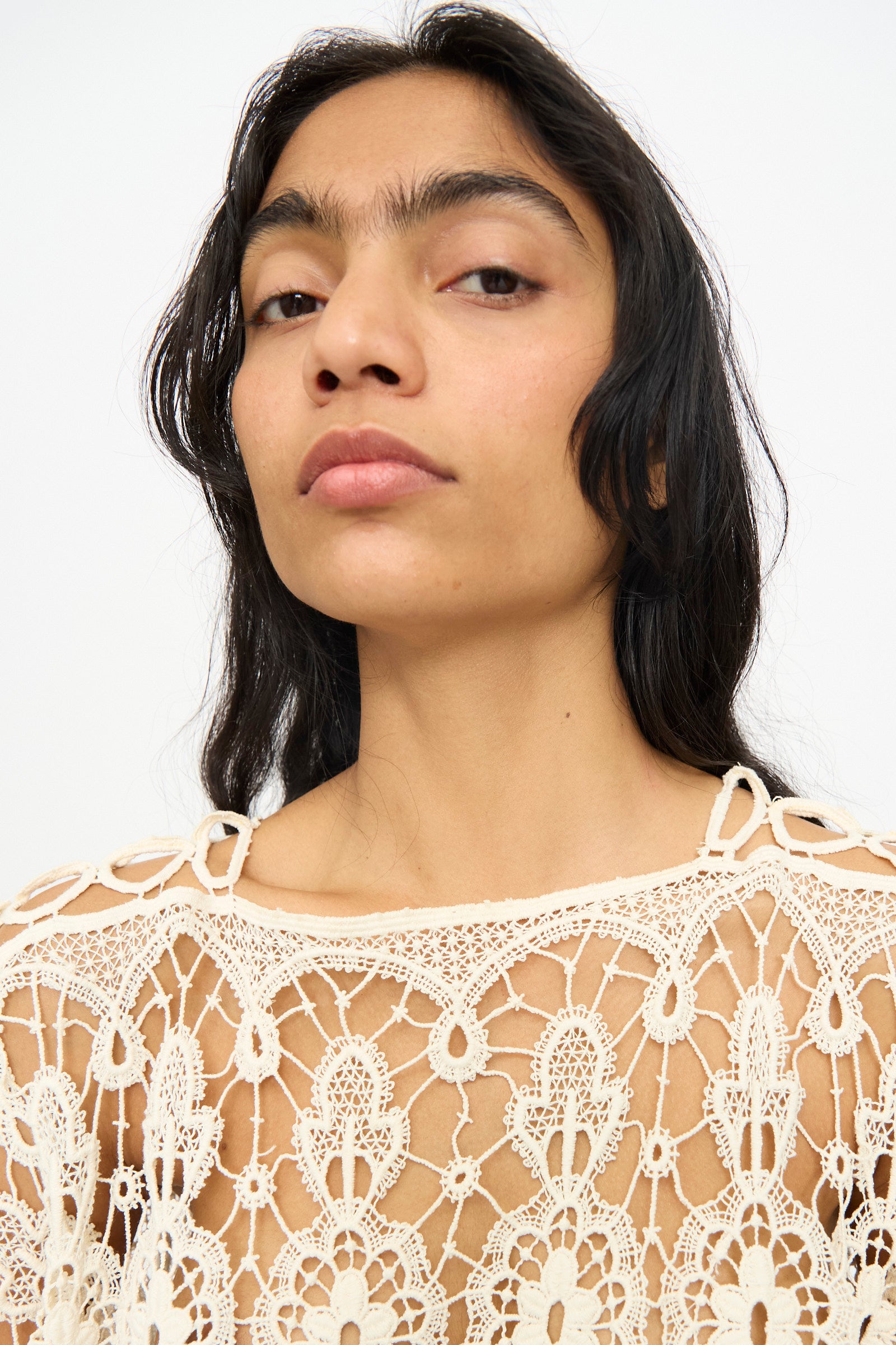 A person with long dark hair models the Antique Lace Midi Caftan by Thank You Have A Good Day, featuring intricate crochet in cream, and looks into the camera against a plain background.