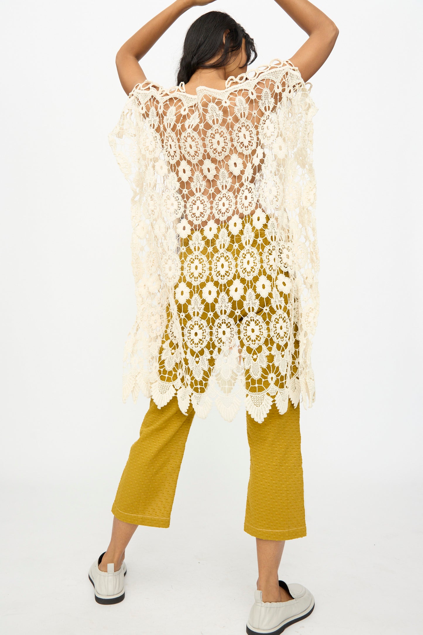 A person faces away, wearing the Thank You Have A Good Day Antique Lace Midi Caftan—a relaxed fit with cream crochet lace—over mustard yellow pants and white slip-ons, set against a plain white background.