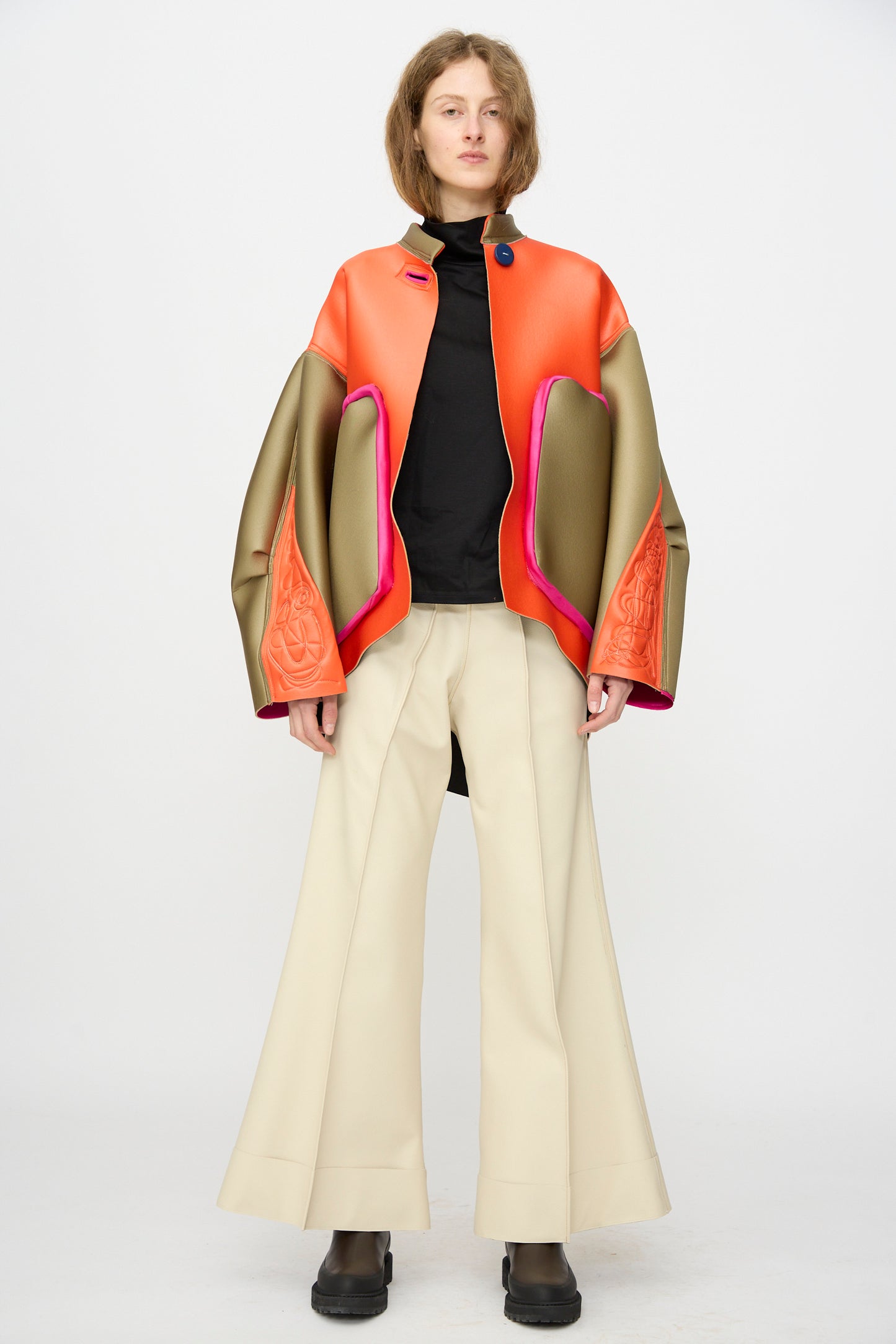 A person poses against a plain backdrop in the Thank You Have A Good Day Color block Cropped Parka, flared beige pants, a black top, and black boots.