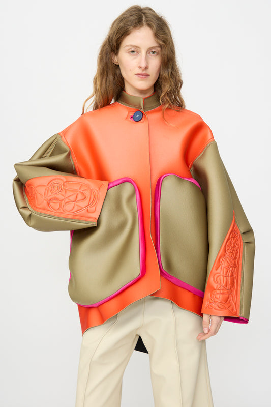 Model wears the Thank You Have A Good Day Color block Cropped Parka in orange, olive green, and pink with oversized sleeves and abstract patterns, paired with beige pants, against a plain background.
