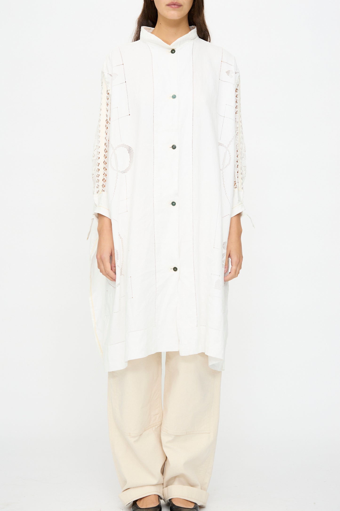 Someone stands against a plain white background wearing the Heart and Flower Oversized Oxford shirt dress by Thank You Have A Good Day, styled over loose beige pants and black shoes.
