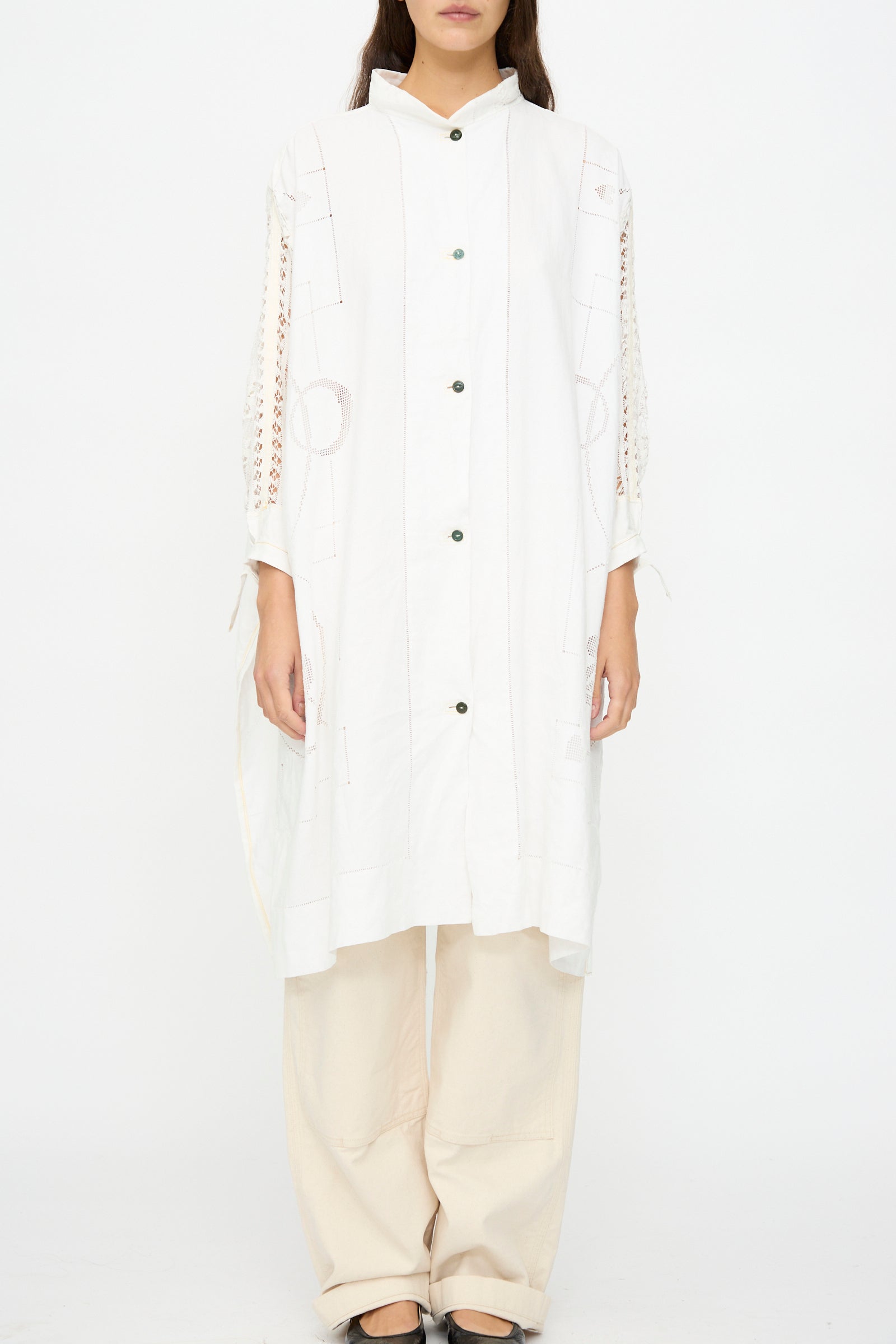 Someone stands against a plain white background wearing the Heart and Flower Oversized Oxford shirt dress by Thank You Have A Good Day, styled over loose beige pants and black shoes.