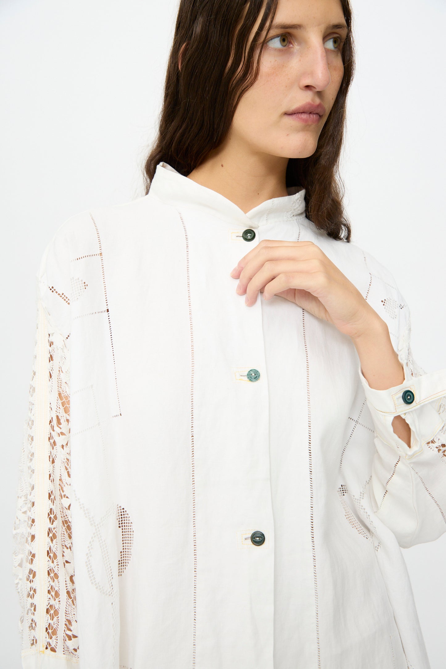 A person with long brown hair wears the Heart and Flower Oversized Oxford by Thank You Have A Good Day, featuring lace sleeve detailing, standing against a plain light background.
