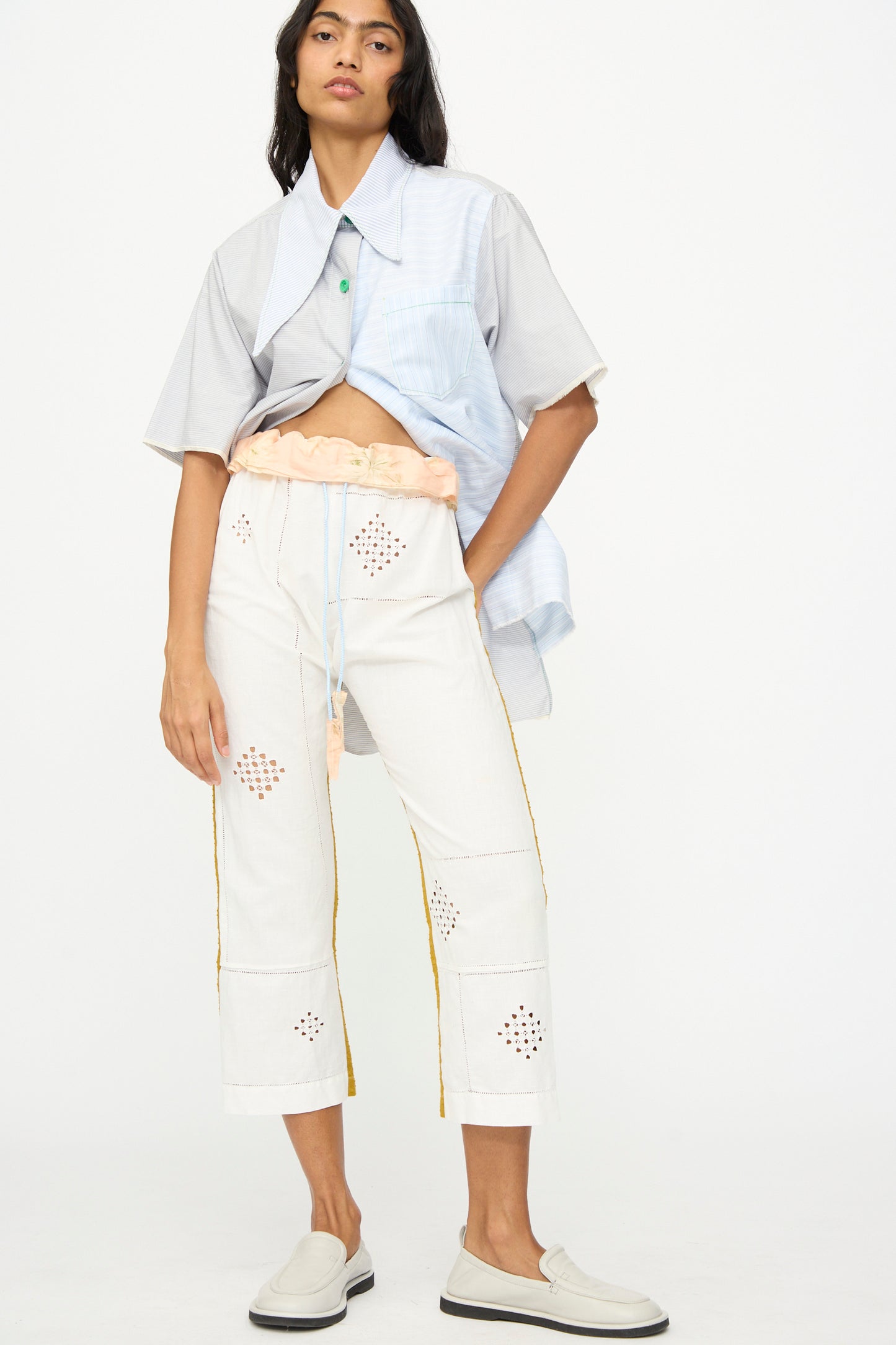 A person wears a loose short-sleeve shirt over a cropped top, paired with the handmade Lounge Pant by Thank You Have A Good Day, featuring cutout patterns, and light slip-on shoes, all photographed against a plain background.