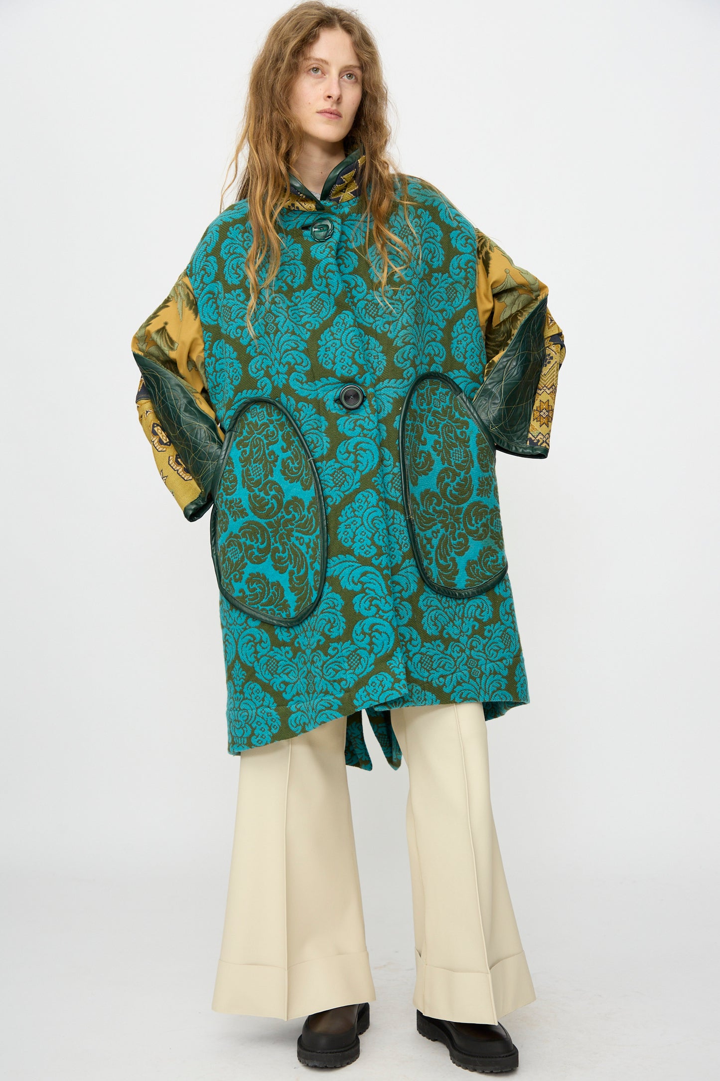 A person with long hair wears the Thank You Have A Good Day Patchwork Fishtail Parka, cream wide-leg pants, and black shoes, standing against a plain white background.