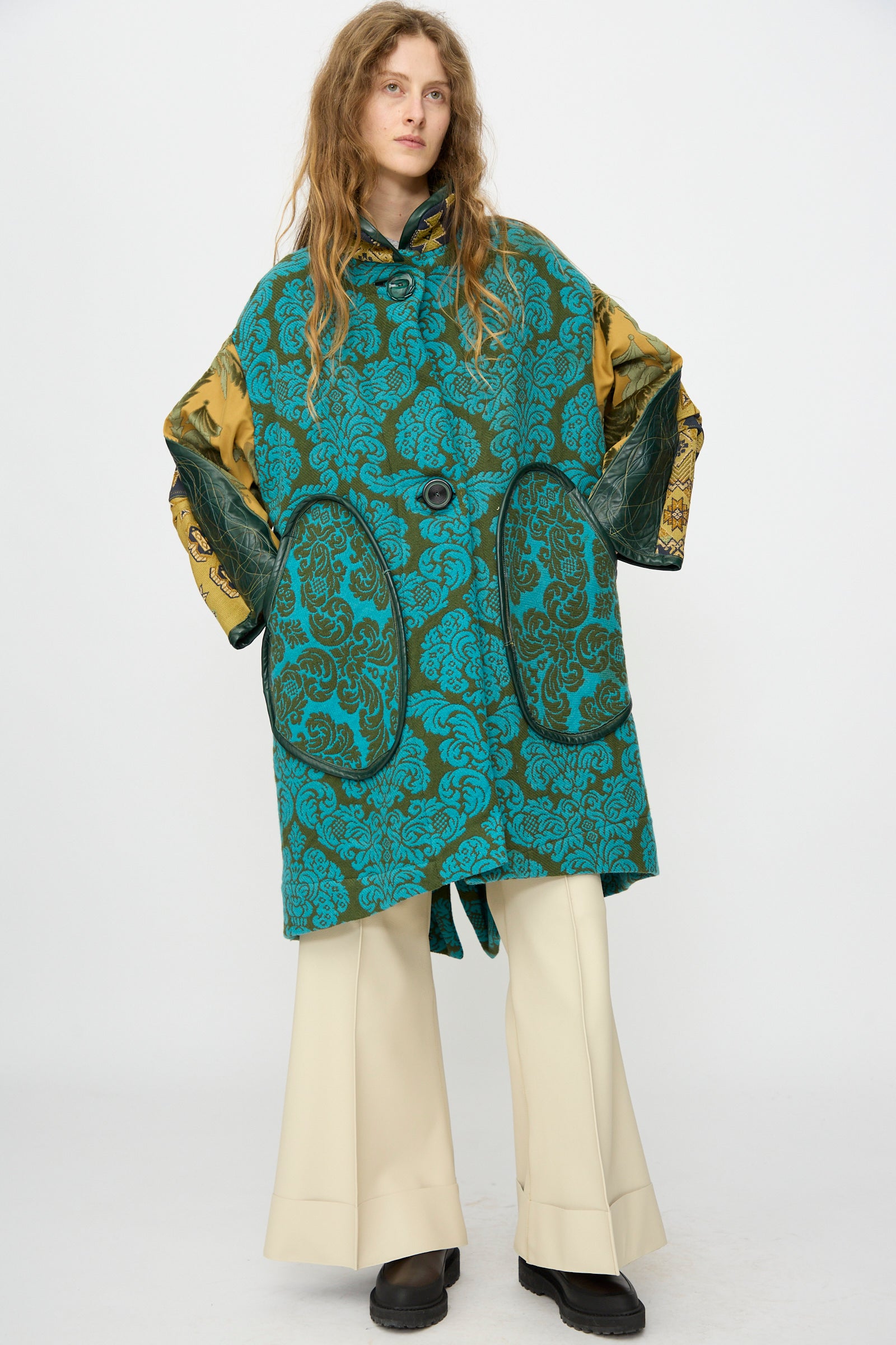 A person with long hair wears the Thank You Have A Good Day Patchwork Fishtail Parka, cream wide-leg pants, and black shoes, standing against a plain white background.