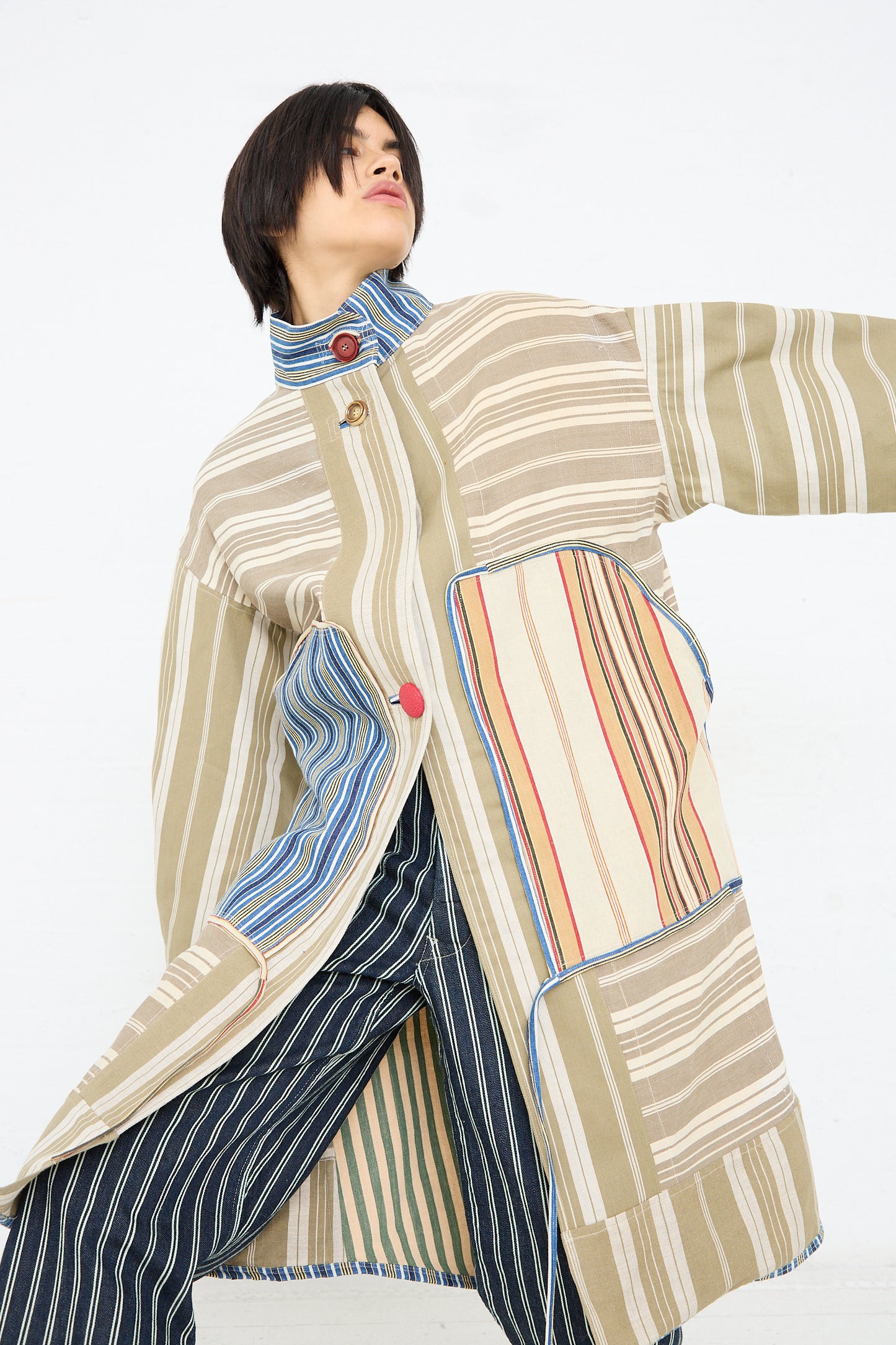 A person wearing a Thank You Have A Good Day Patchwork French Ticking Fishtail Parka with an oversized silhouette is standing in a dynamic pose against a white background.