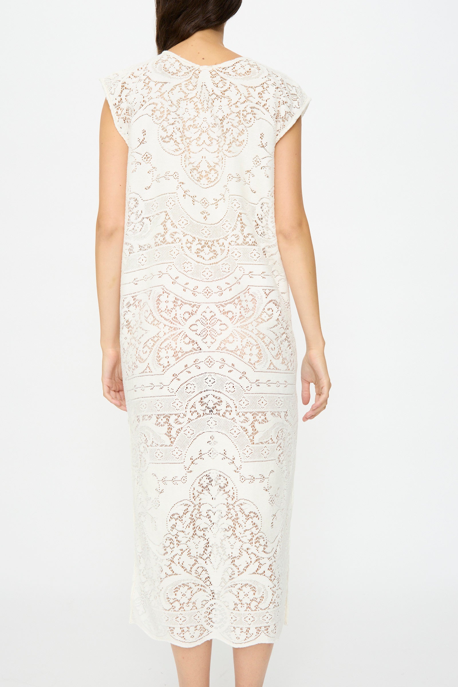 A woman faces away, wearing the Thank You Have A Good Day Quaker Lace Caftan—a white, calf-length dress with intricate antique quaker lace patterns and short sleeves.