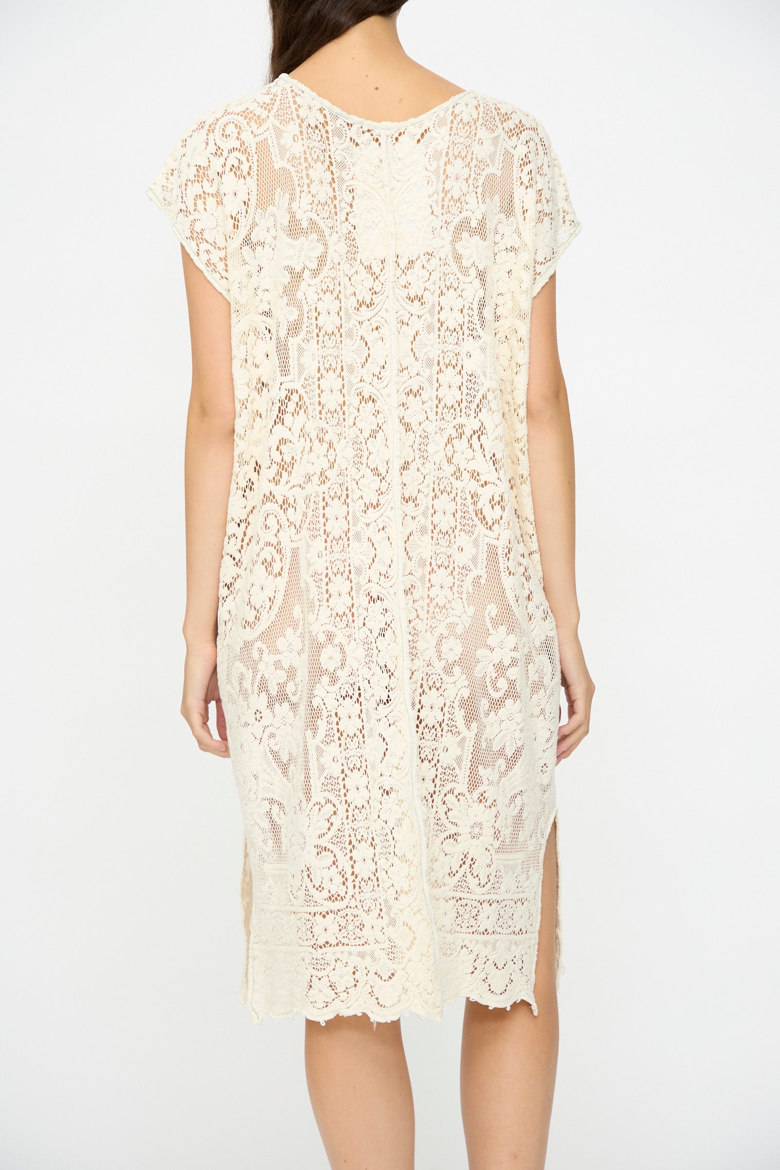 A woman is shown from the back wearing the Quaker Lace Caftan Midi Pullover by Thank You Have A Good Day—a cream, knee-length, short-sleeve lace dress with a floral pattern and scalloped hem, made in New York from antique Quaker lace.