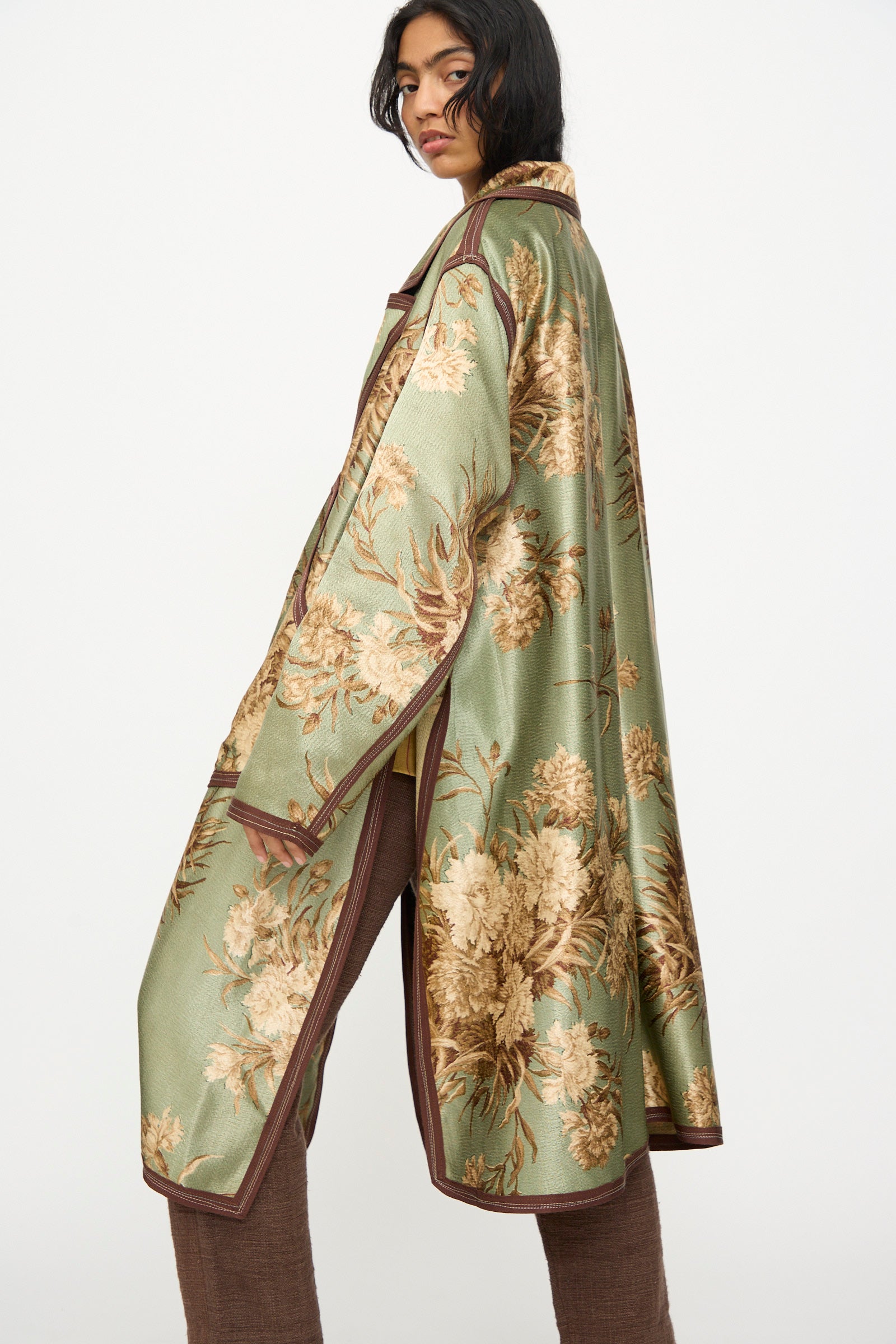 Wearing the Thank You Have A Good Day Taped Trench in Floral, this person stands sideways against a plain white background.