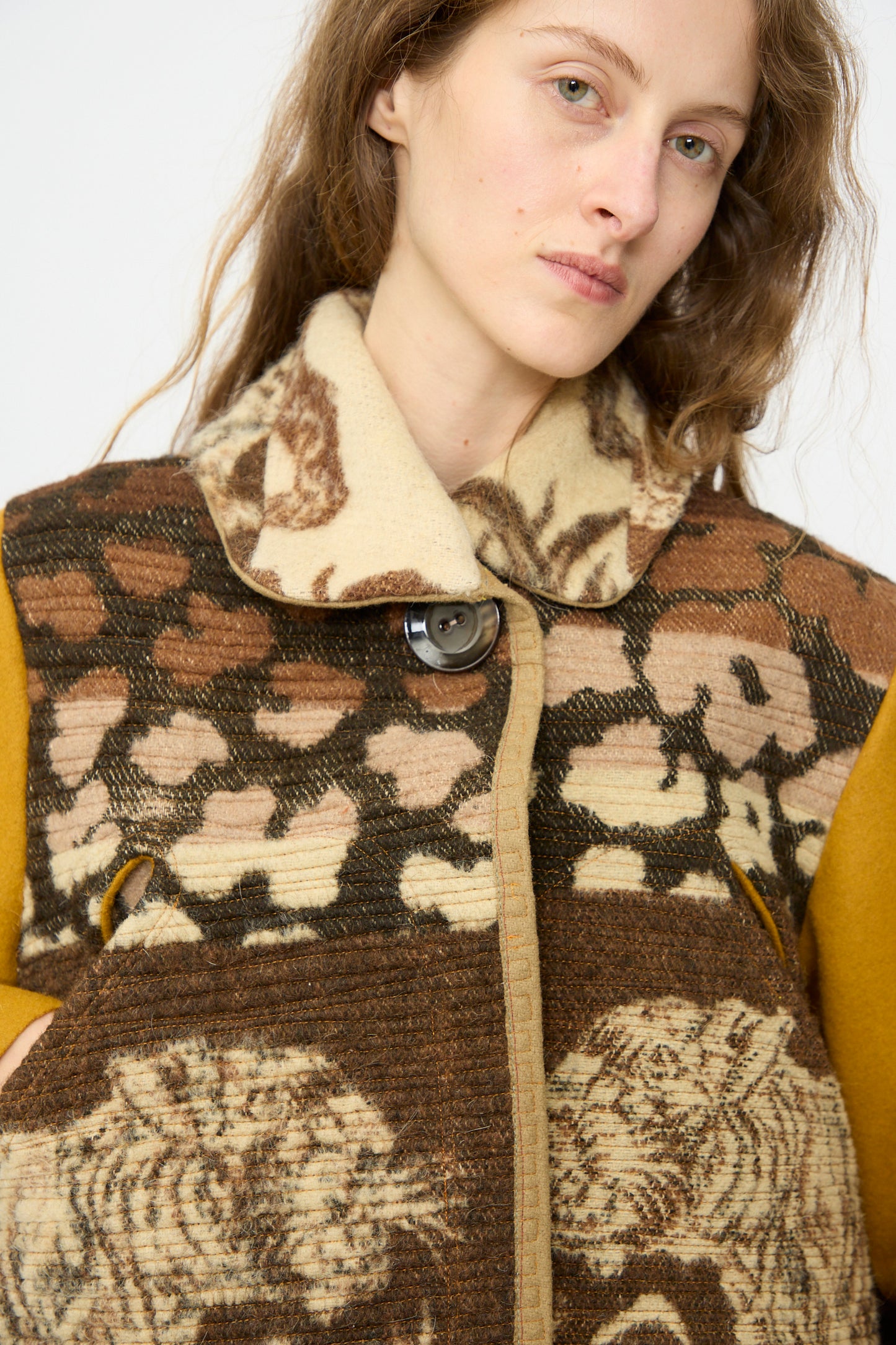 A woman with long brown hair wears the Thank You Have A Good Day Tiger Topper Jacket, a patterned brown and beige 1930s wool piece with a large button and wide collar, looking slightly off-camera.