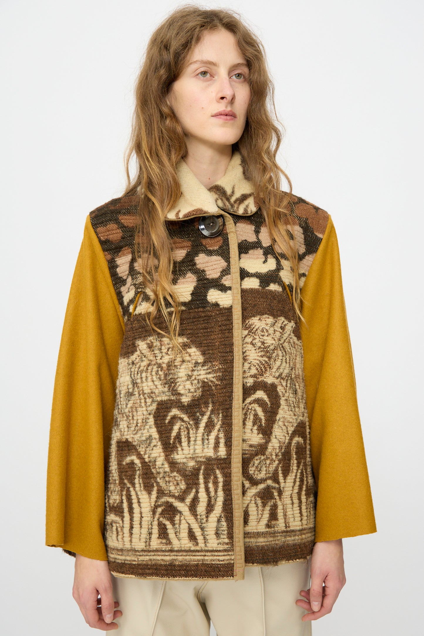 A person with long wavy hair models the Tiger Topper Jacket by Thank You Have A Good Day, crafted from a 1930s wool tiger blanket with brown and yellow tiger and grass patterns, set against a plain light background.