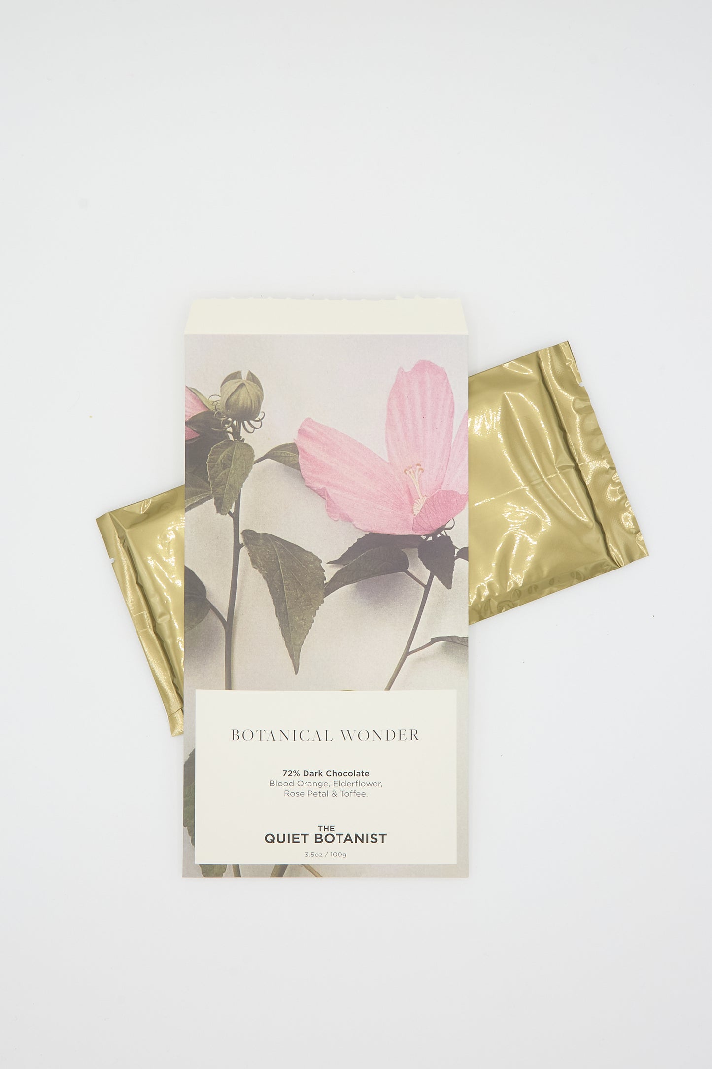 Experience the allure of botanical dark chocolate with The Quiet Botanist's Botanical Wonder Bar, wrapped in a charming beige and gold design featuring floral illustrations. This exquisite chocolate bar showcases 72% dark chocolate infused with prickly pear and tarragon.