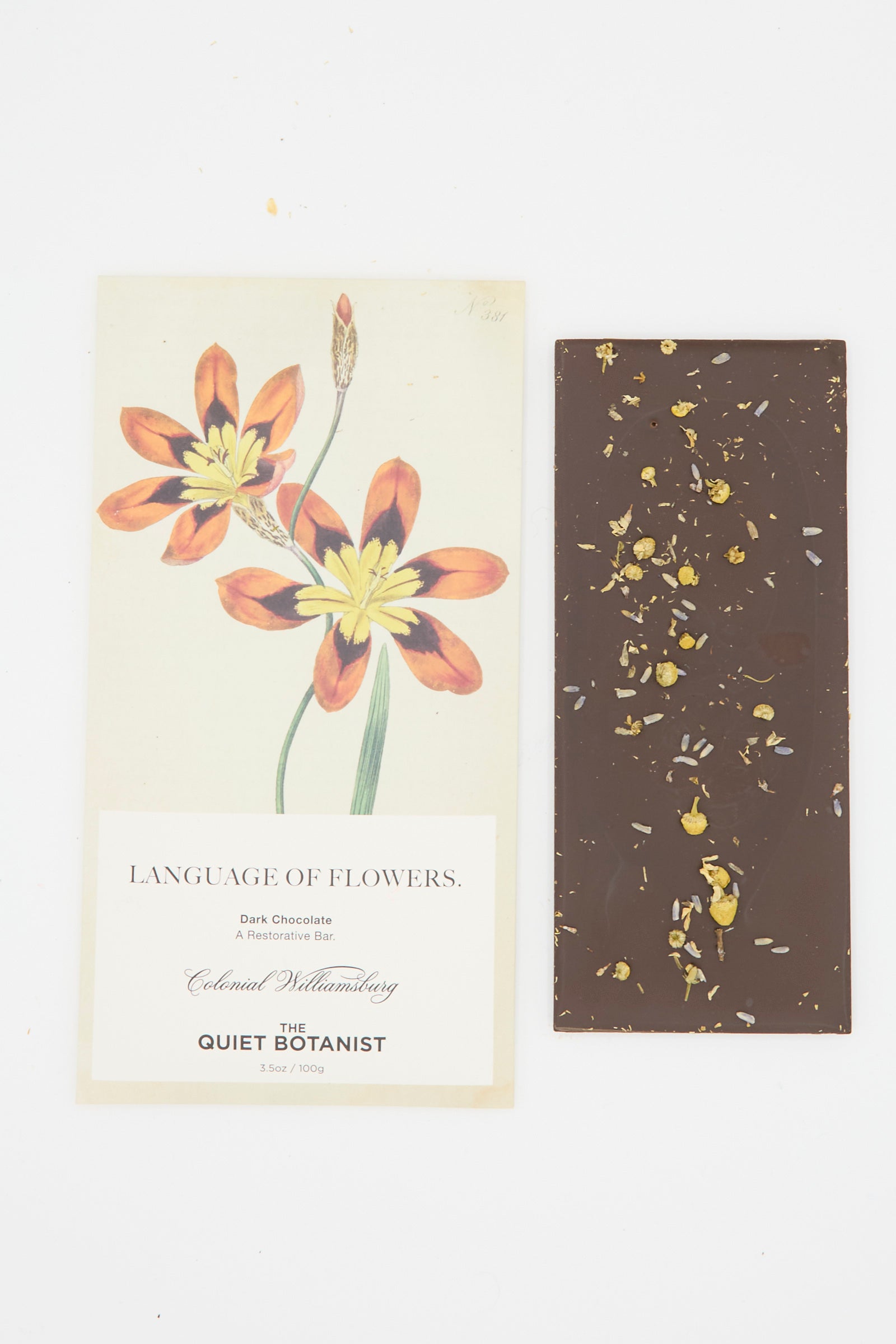 The Language of Flowers Bar by The Quiet Botanist, a dark chocolate bar with flower petals, is paired with packaging featuring an orange and yellow flower illustration.