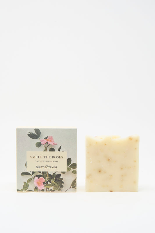 A vegan Smell The Roses Soap Bar by The Quiet Botanist stands beside its floral box, which hints at the artisanal Turkish craftsmanship within.