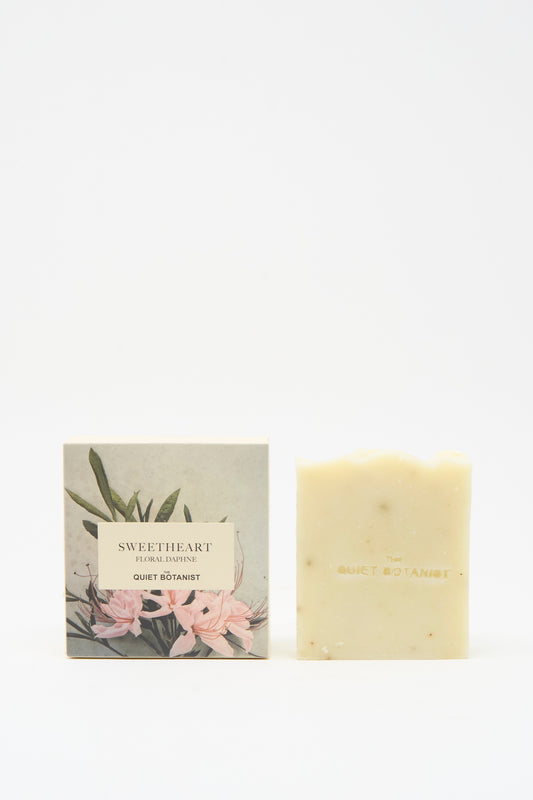 The Quiet Botanist Sweetheart Floral Daphne Soap Bar, handmade in Turkey for sensitive skin, sits by its floral-illustrated box labeled "Sweetheart Floral Botanical.