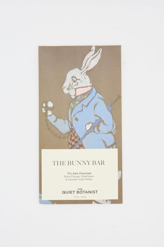 The Quiet Botanist’s The Bunny Bar is a 77% dark chocolate bar infused with botanicals like elderflower, featuring a white rabbit in a blue coat on the package.