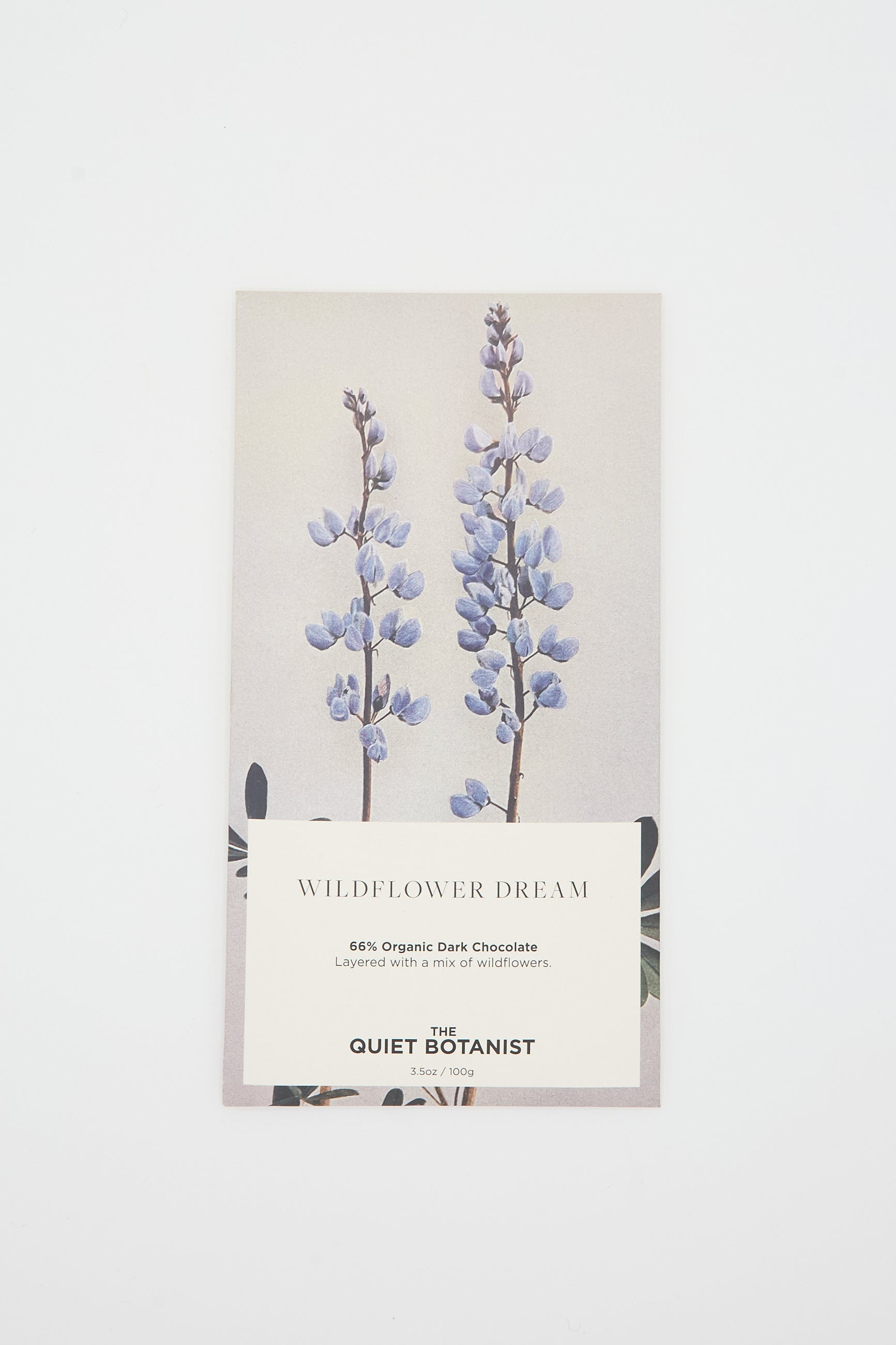 A chocolate bar called the Wildflower Dream Bar by The Quiet Botanist, made with 66% organic dark chocolate and dried wildflowers. The packaging features two purple wildflowers.