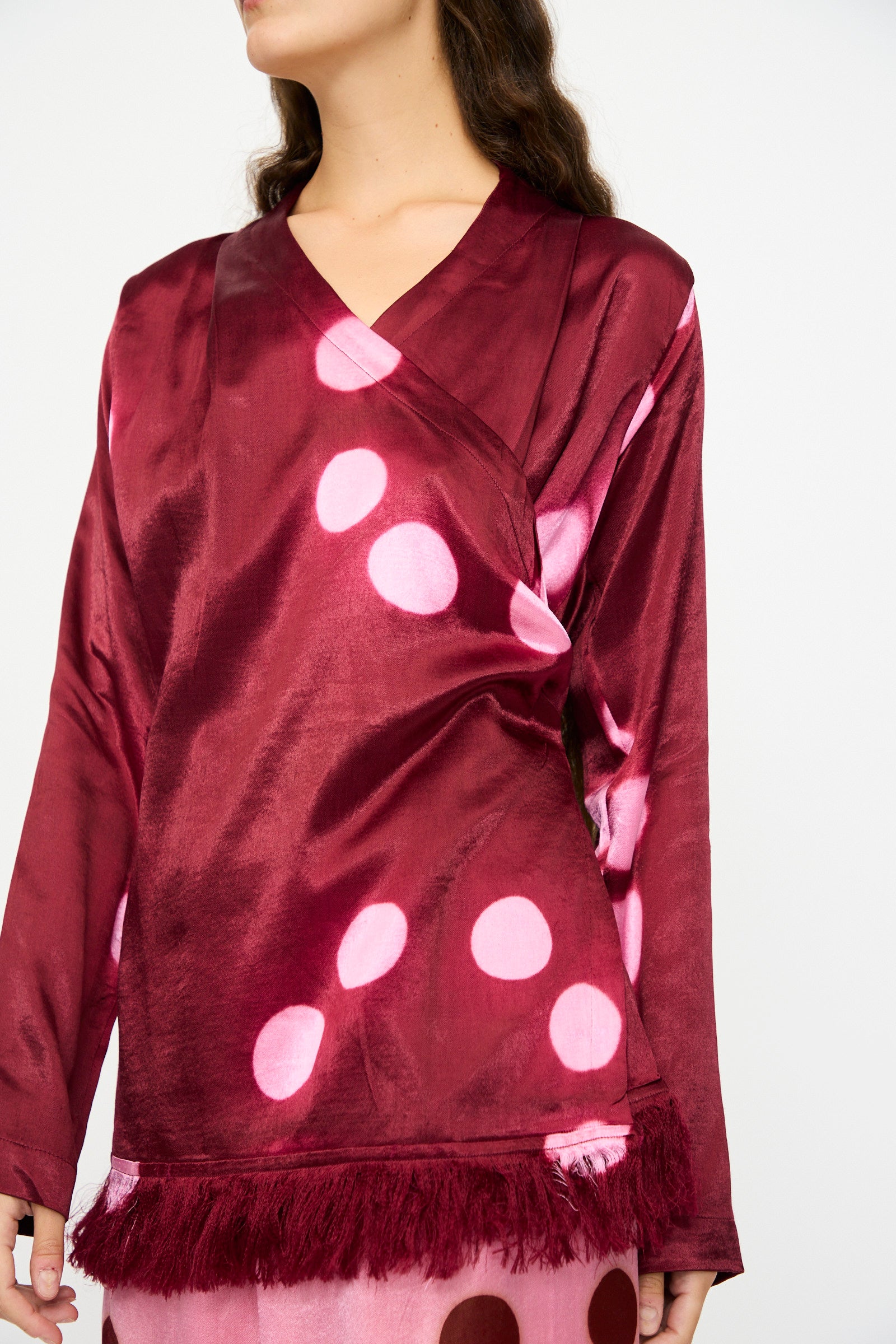 A woman wears the TIGRA TIGRA Silk Mashroo Moon Dye Wrap Top in maroon.