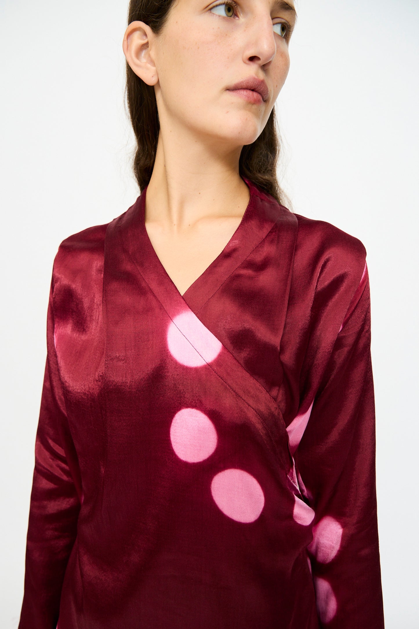 A woman wearing the TIGRA TIGRA Silk Mashroo Moon Dye Wrap Top in Maroon stands against a plain white background.