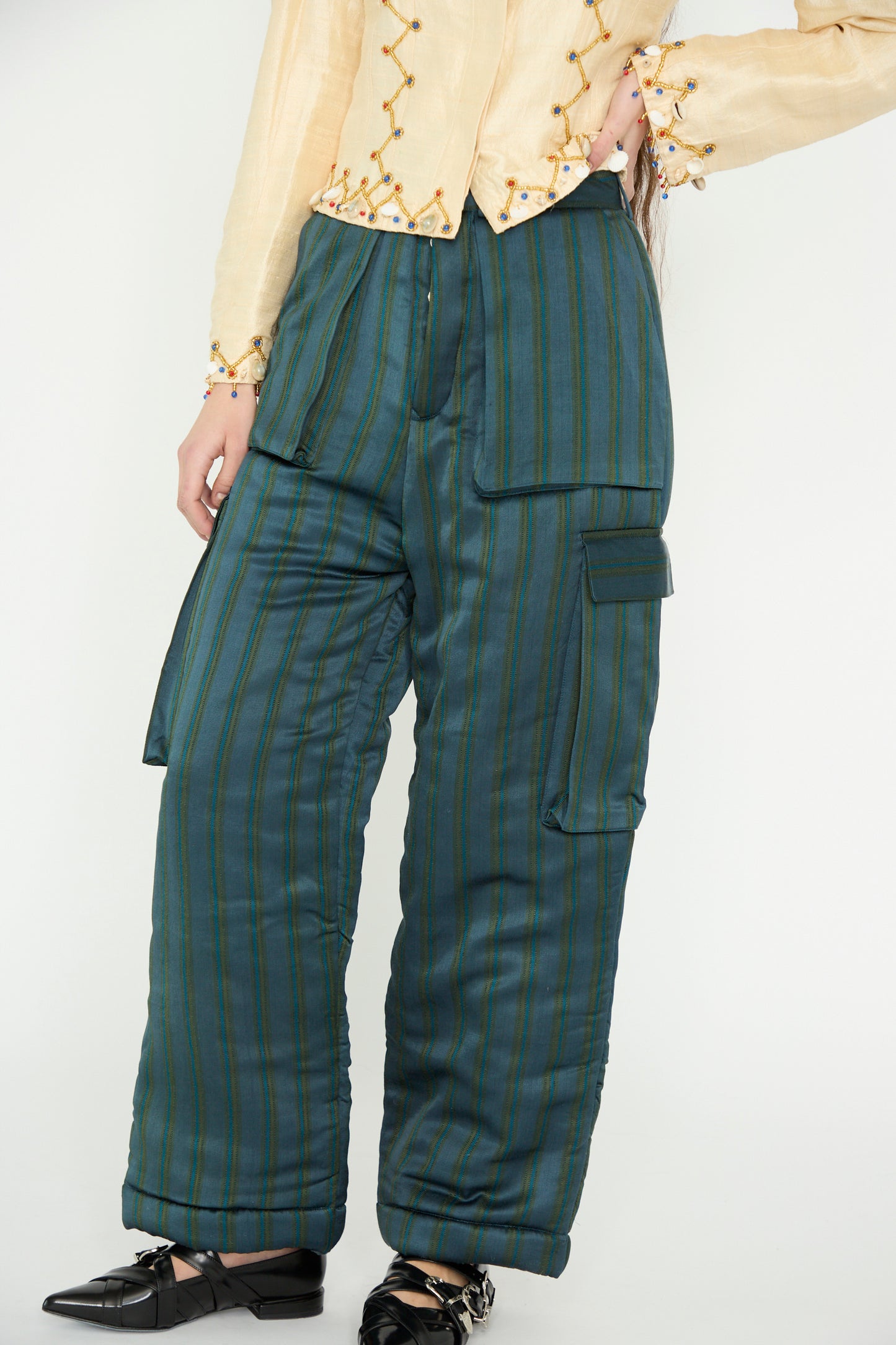 A model poses with one hand on their hip against a plain backdrop, in black shoes, wearing a yellow blouse and TIGRA TIGRA's Striped Aviator Puff Pant in Navy Stripe.