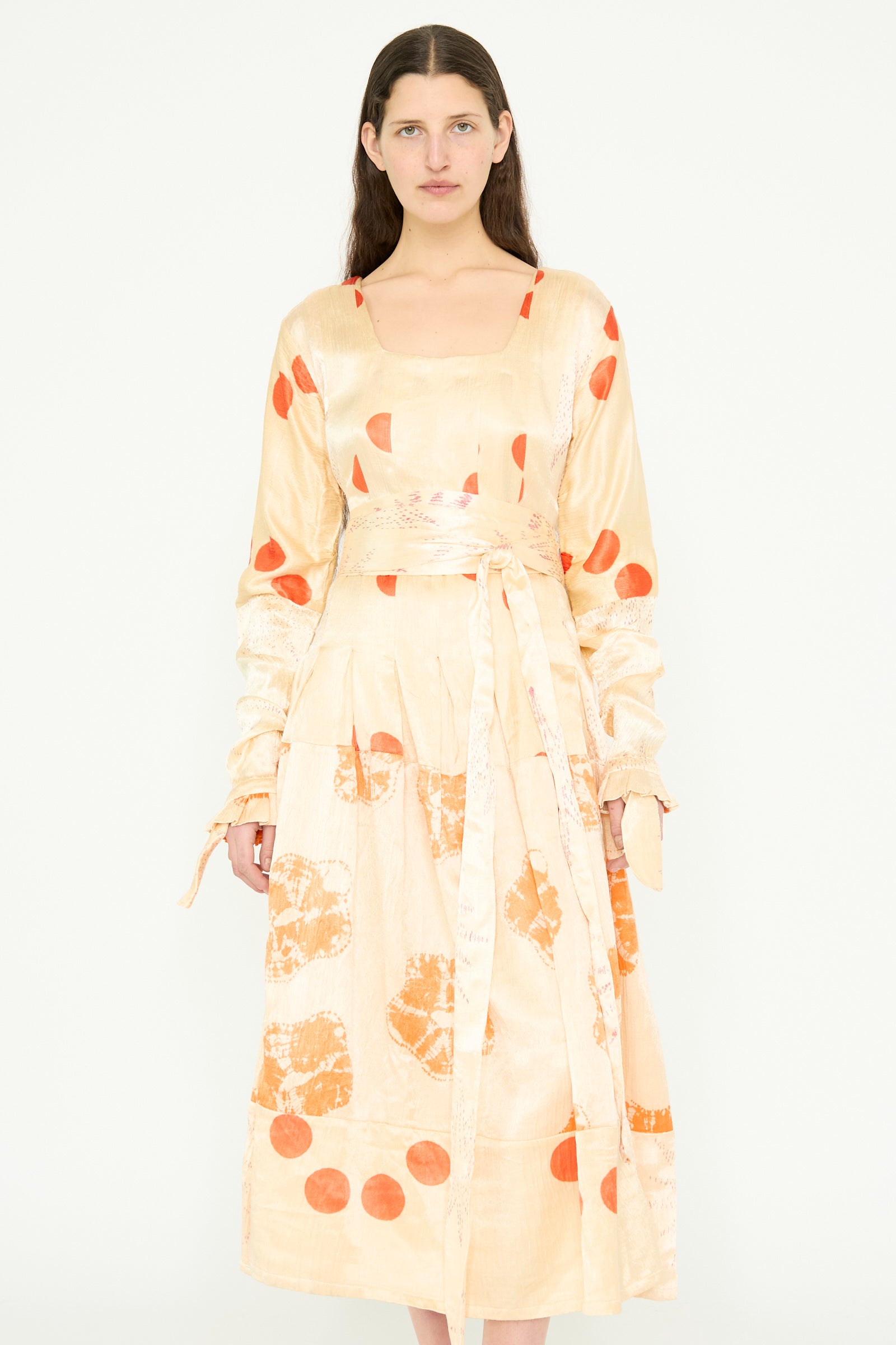 A model  is wearing the TIGRA TIGRA Tropical Dress with Patchwork Tie Dye in Pale Grey and Orange Bandhej, standing against a plain white background.