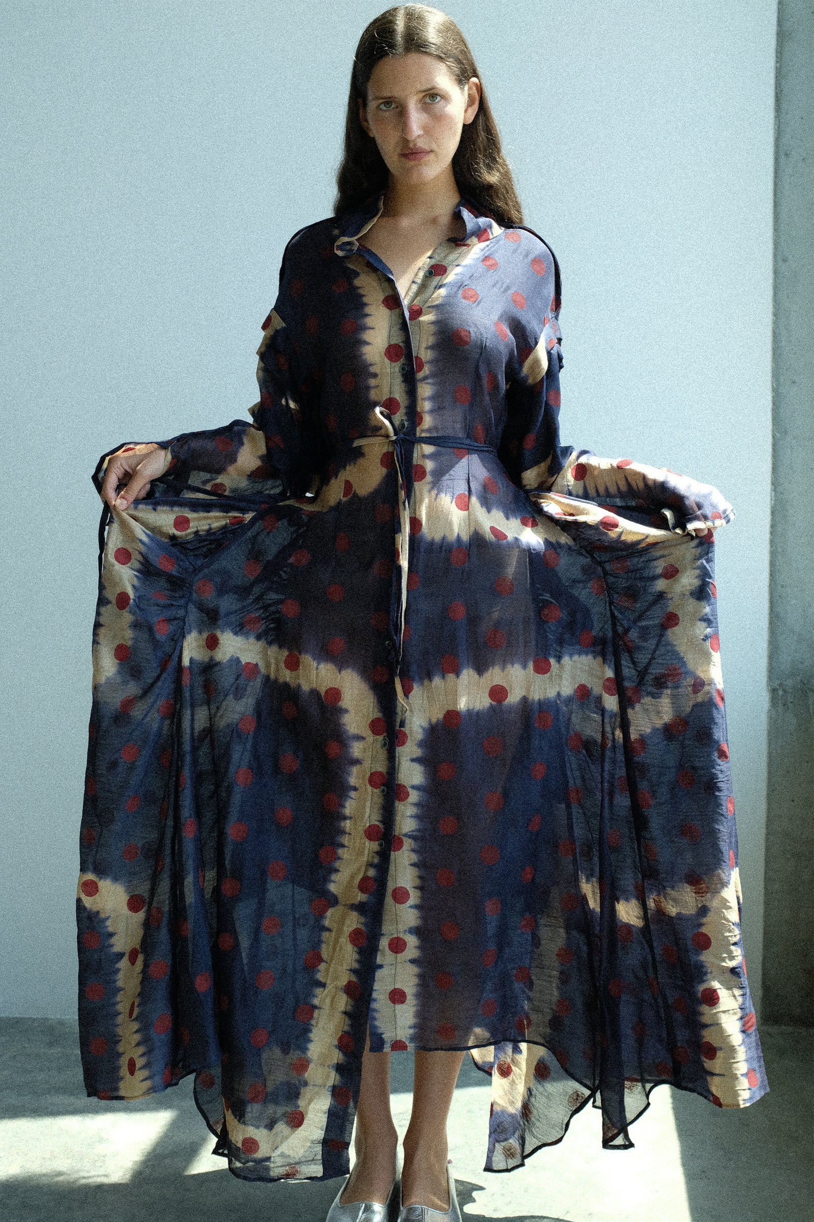 Woman wearing a long, patterned dress with a plain background