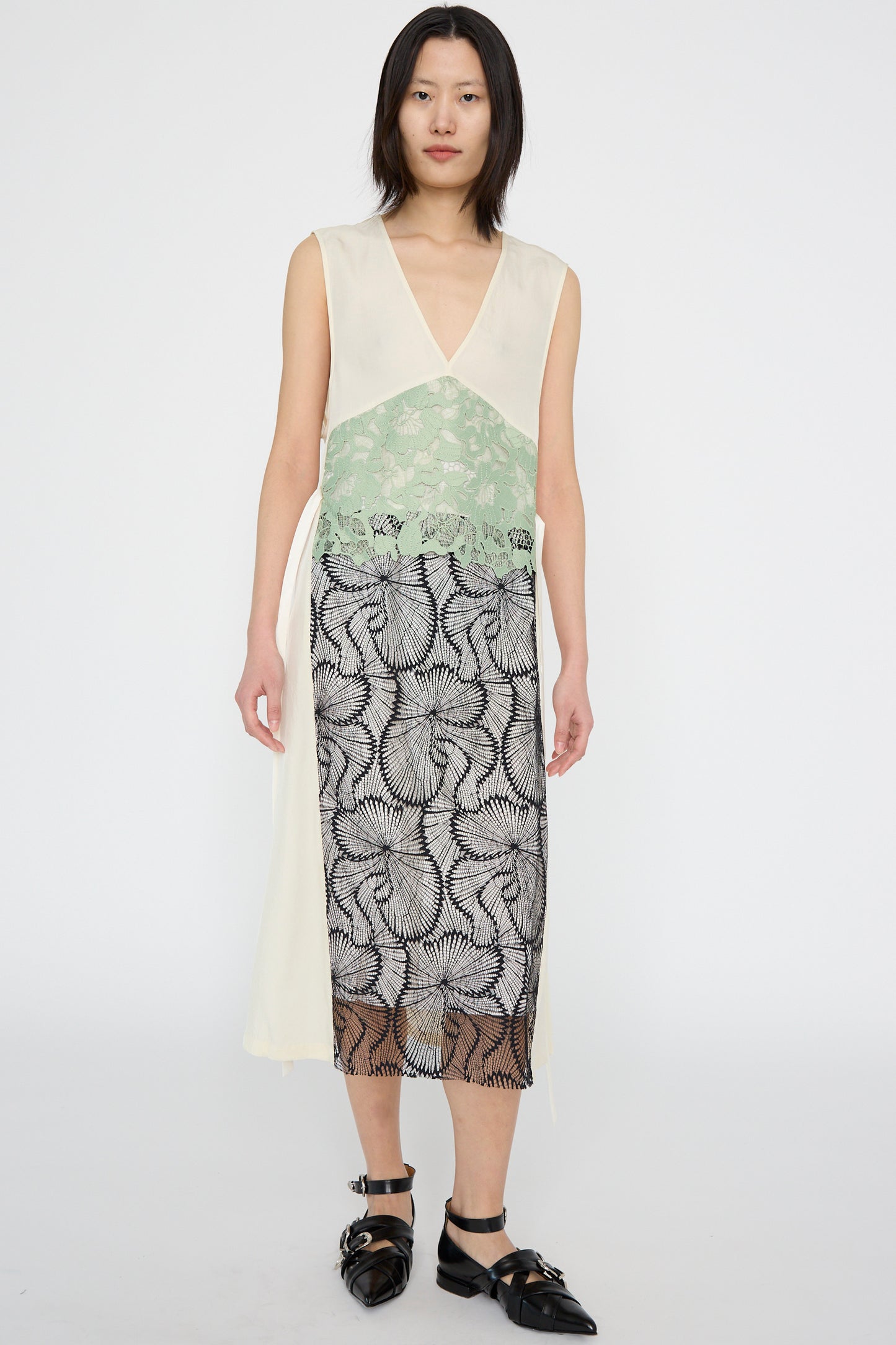 A person wearing an Acetate Twill Lace Dress in Off White by TOGA ARCHIVES stands against a plain background, showcasing the simplicity of its design.