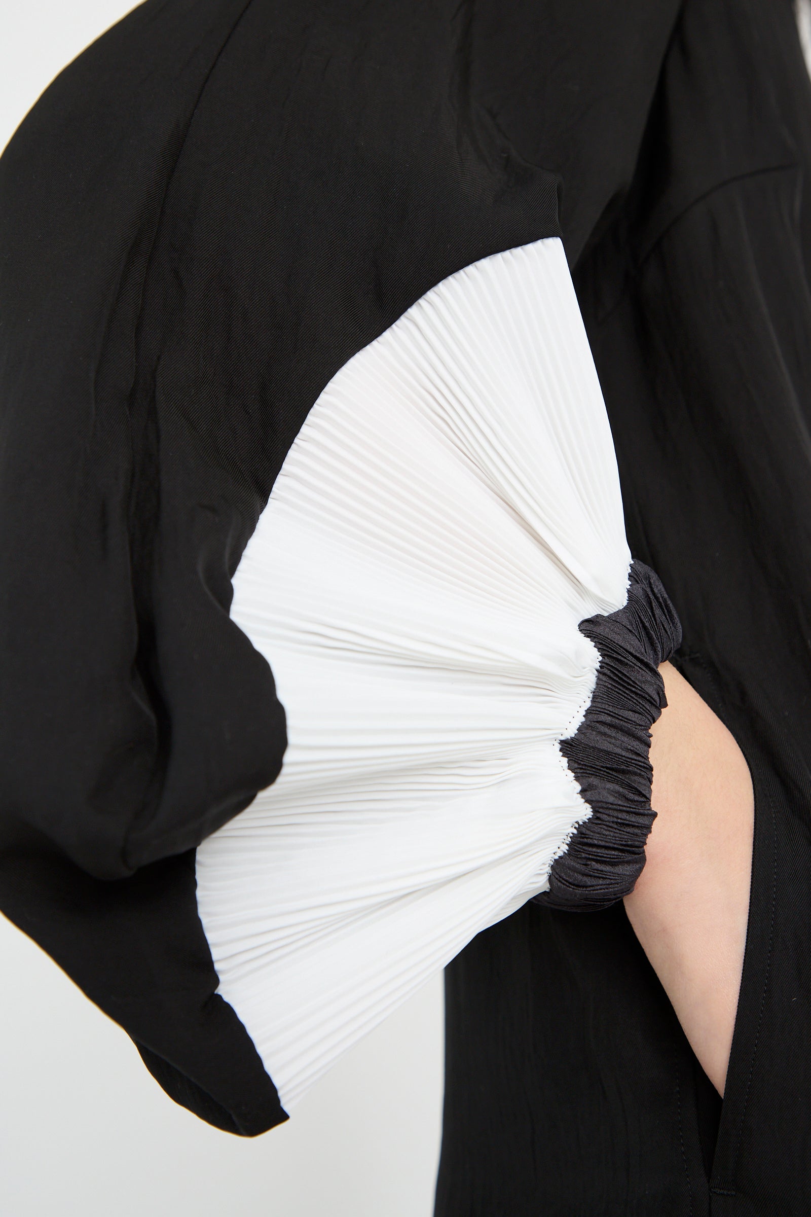 Close-up of the TOGA ARCHIVES Acetate Twill Pleats Dress in Black: features bishop-style sleeves with contrasting white pleated detail and black elastic ends.