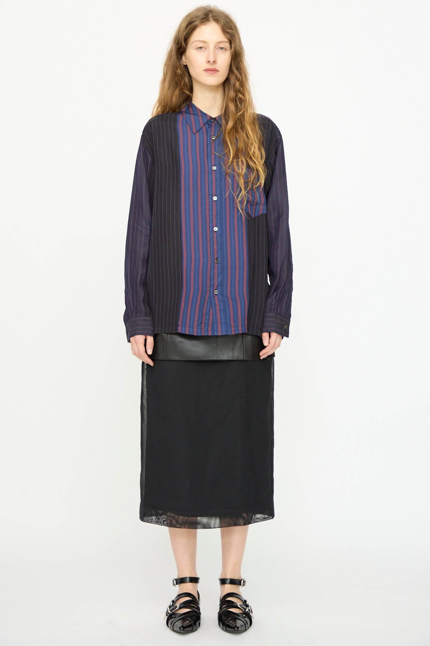 A person wears the TOGA ARCHIVES Cupra Stripe Shirt in Navy with a black skirt and black sandals, standing against a plain white background.