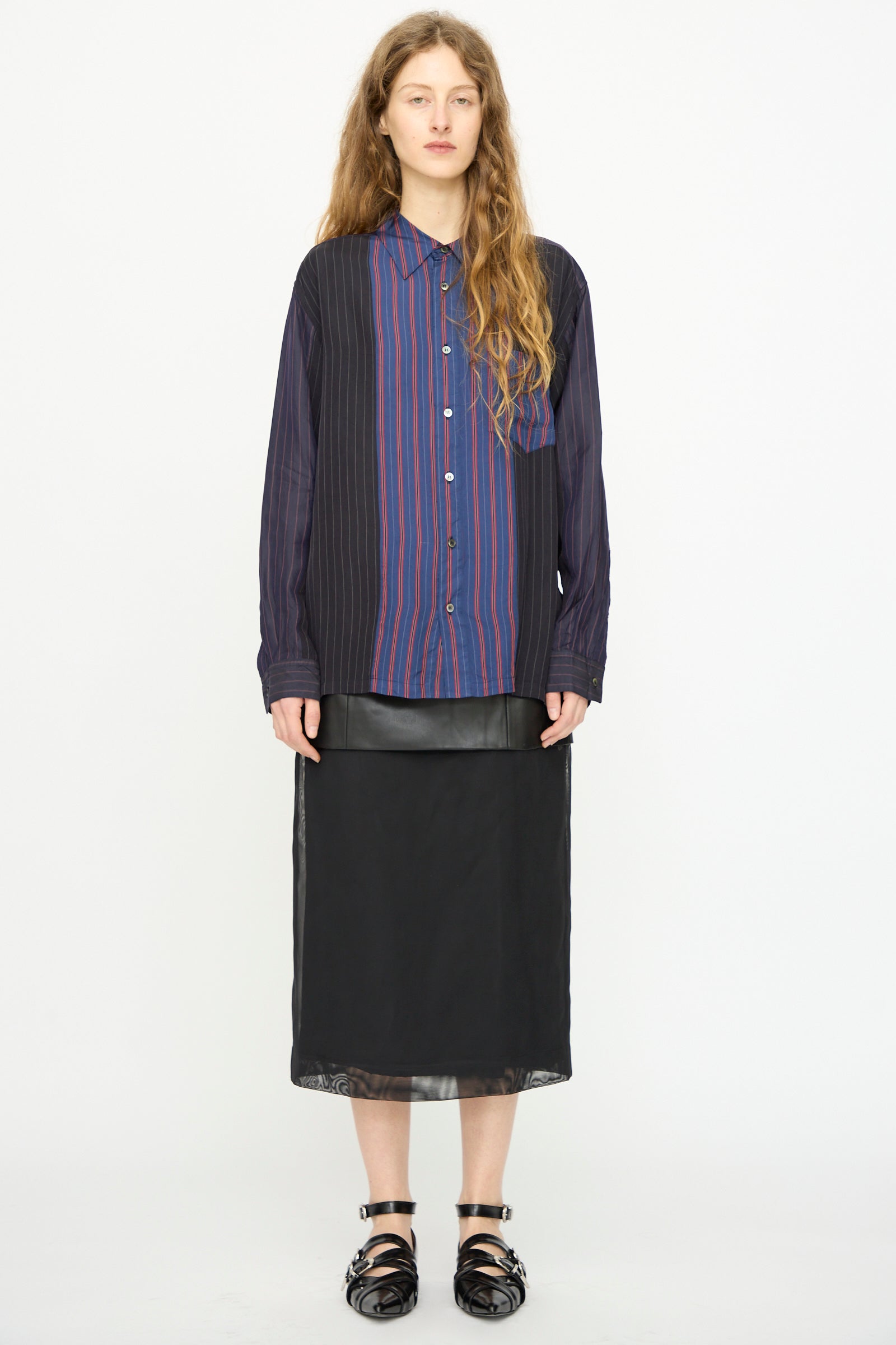 A person wears the TOGA ARCHIVES Cupra Stripe Shirt in Navy with a black skirt and black sandals, standing against a plain white background.
