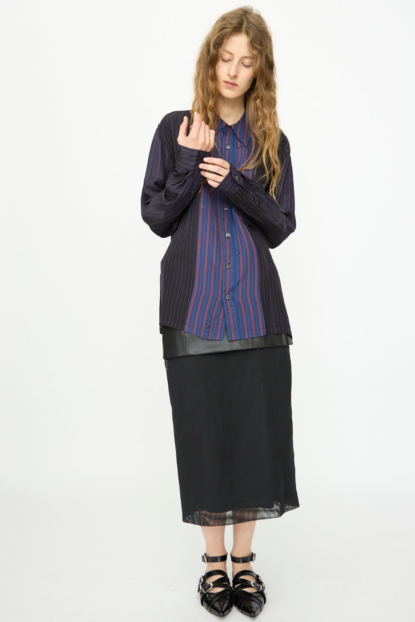 A person wears the TOGA ARCHIVES Cupra Stripe Shirt in Navy, a black midi skirt, and black pointed shoes while standing against a plain white background.